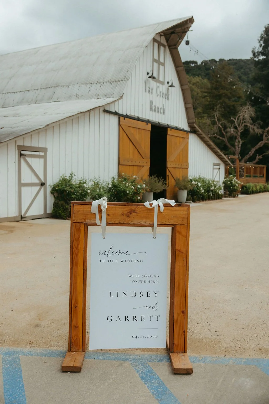 Wedding welcome sign in front of the white Tar Creek Ranch barn