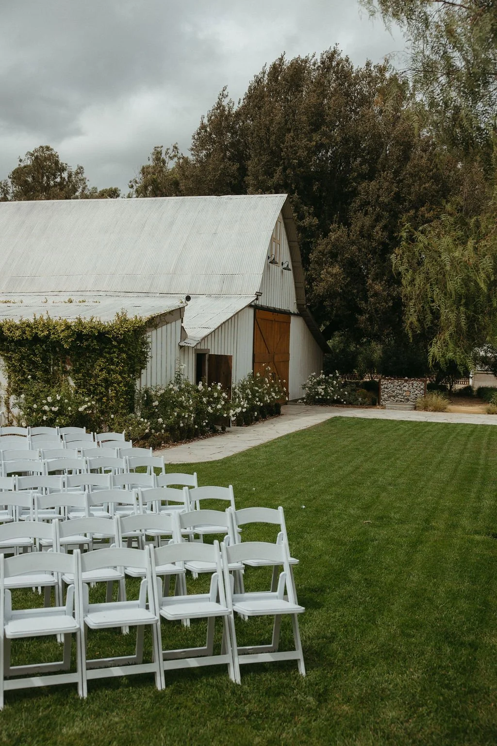 White ceremony chairs arranged in the Garden beside the barn