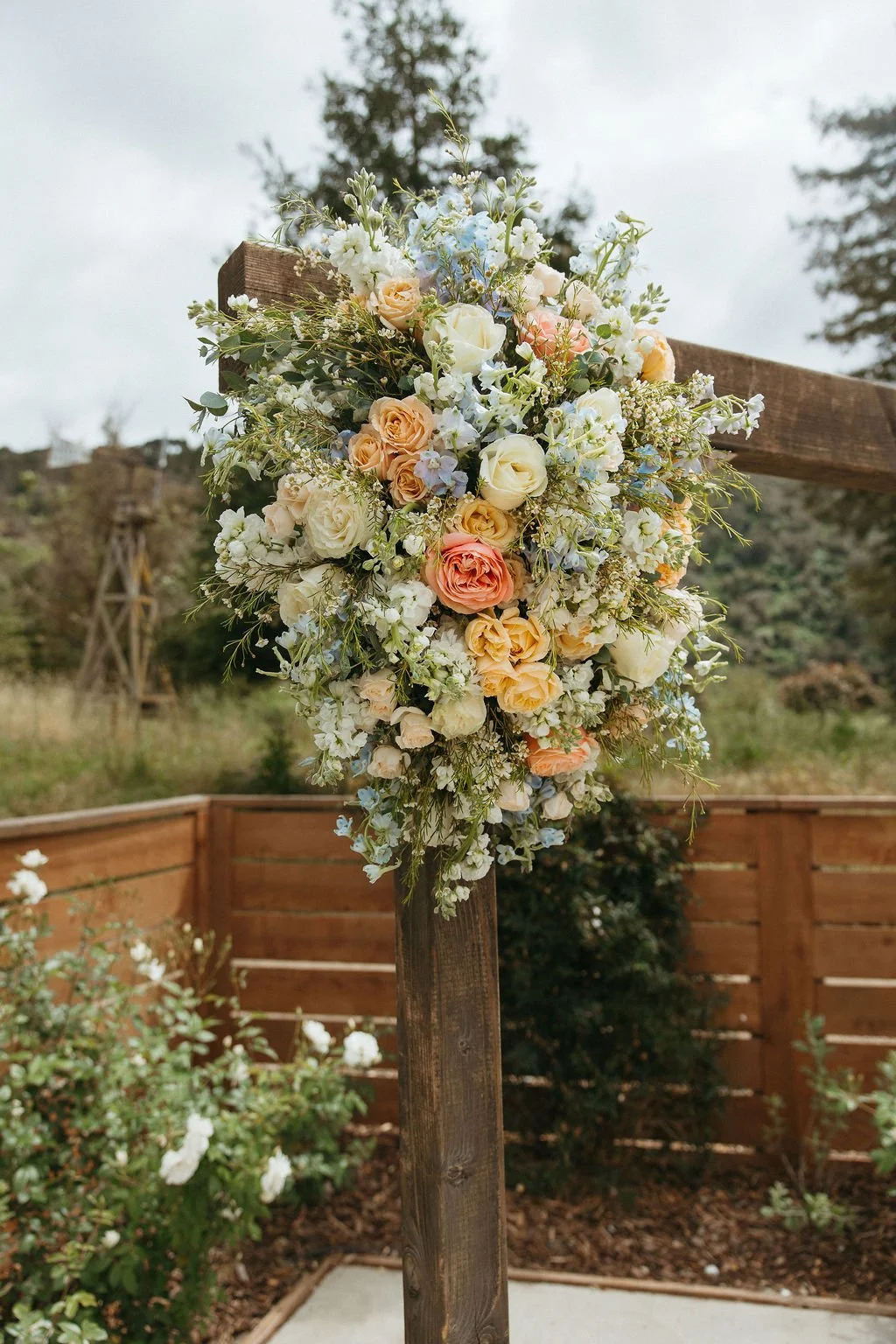 Close view of peach, white, and blue flowers on the ceremony arch