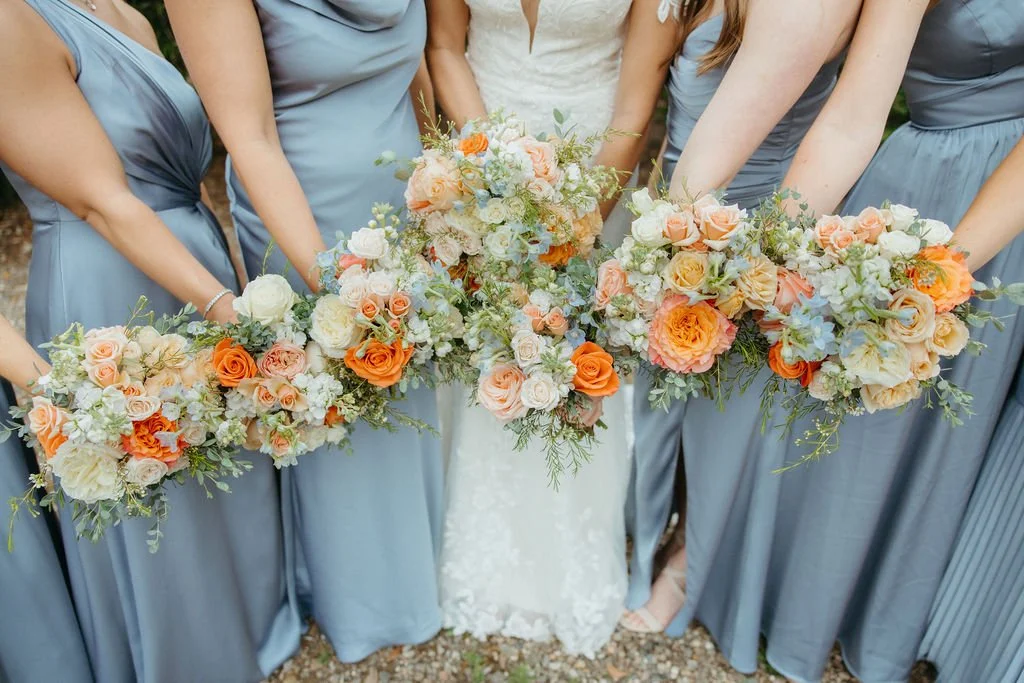Bridesmaid bouquets with peach white orange and blue spring flowers