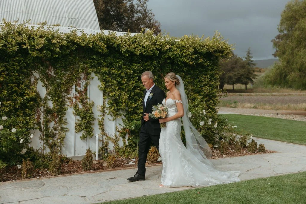 Bride walking beside the historic barn at a Central Coast ranch wedding