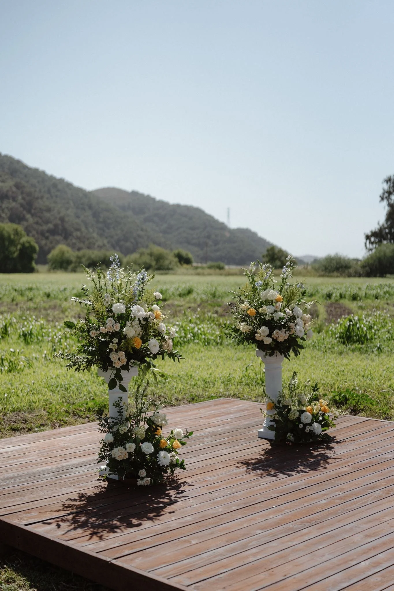 Cream yellow and pale blue floral pillars for a Meadow wedding ceremony