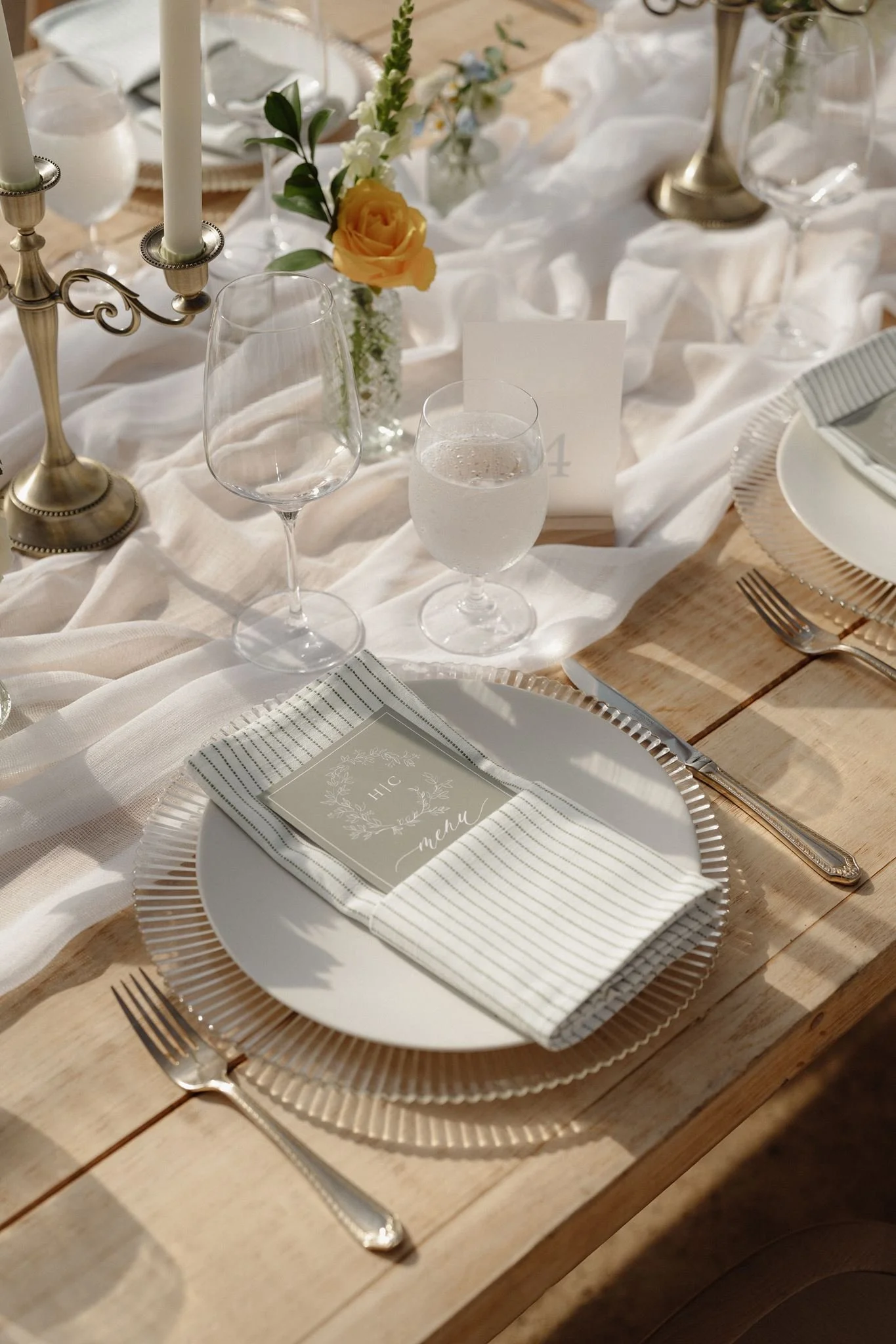 Elegant wedding place setting with striped napkin and brass candleholders