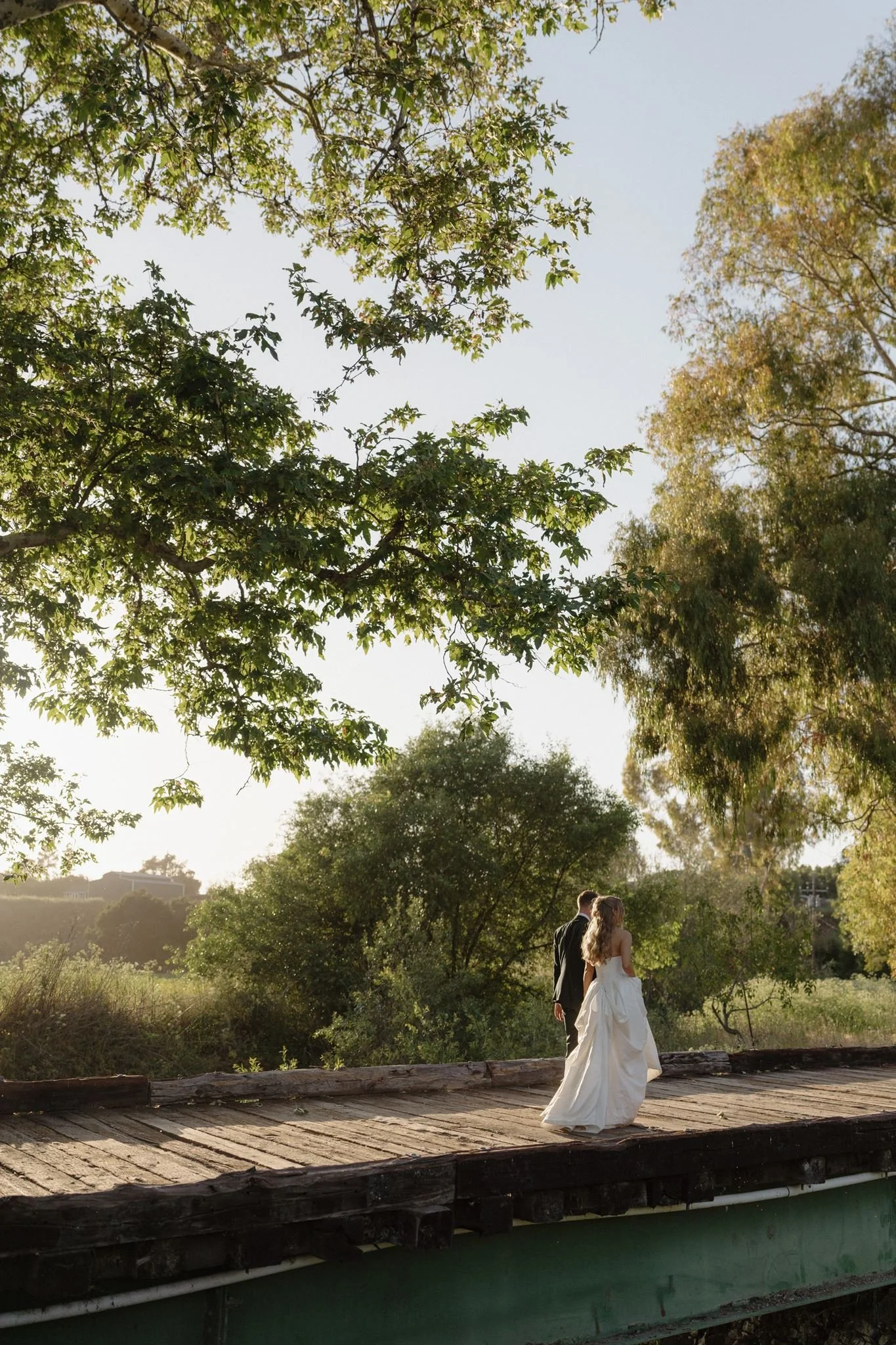 Newlyweds walking across the Tar Creek Ranch bridge at golden hour
