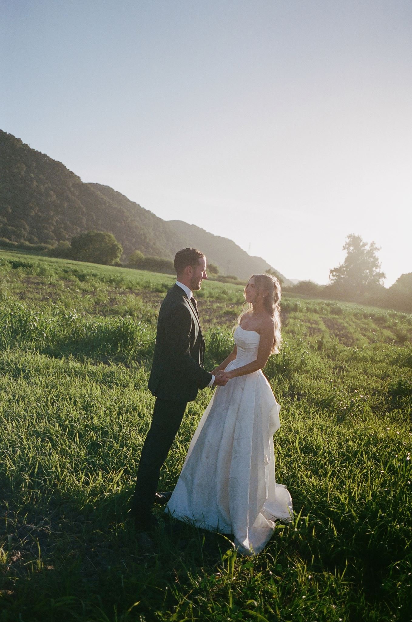 Hannah and Connor holding hands during golden-hour wedding portraits