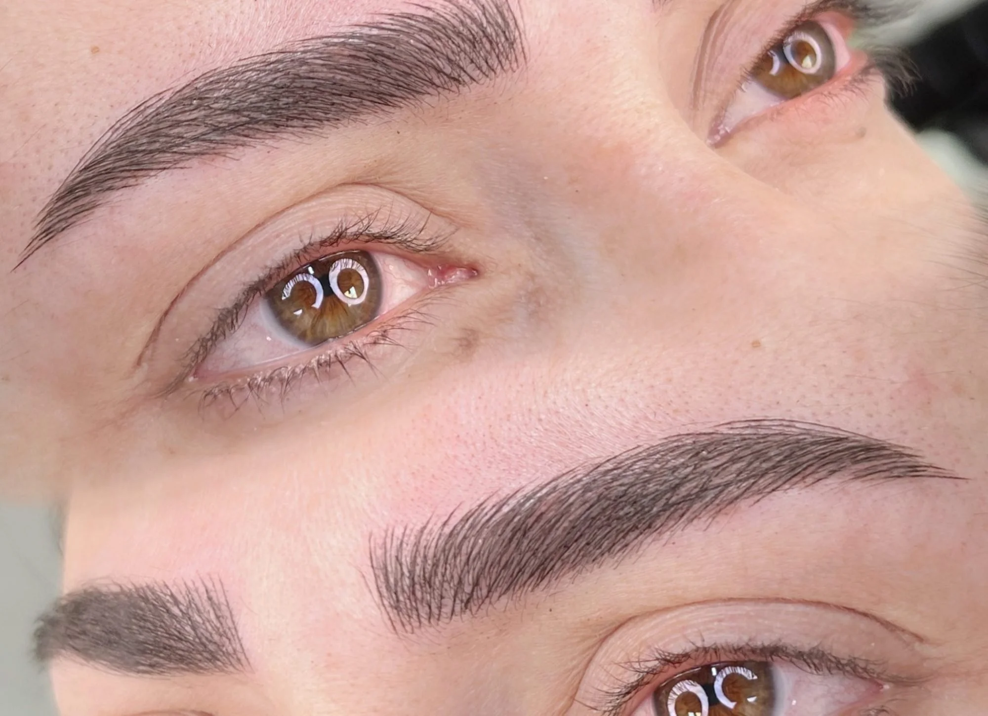 Close-up of a person's face with focus on eyebrows and hazel eyes.