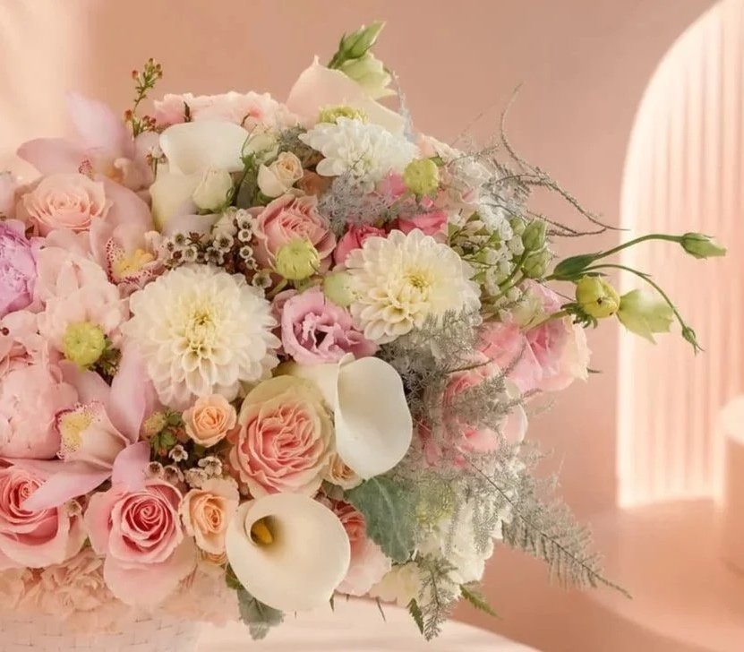 Soft pink and white floral bouquet with roses, calla lilies, and other flowers against a pastel pink background.