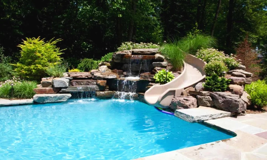 Custom pool with a natural stone waterfall and slide, built by Bottom Line Renovations in Charlotte, NC