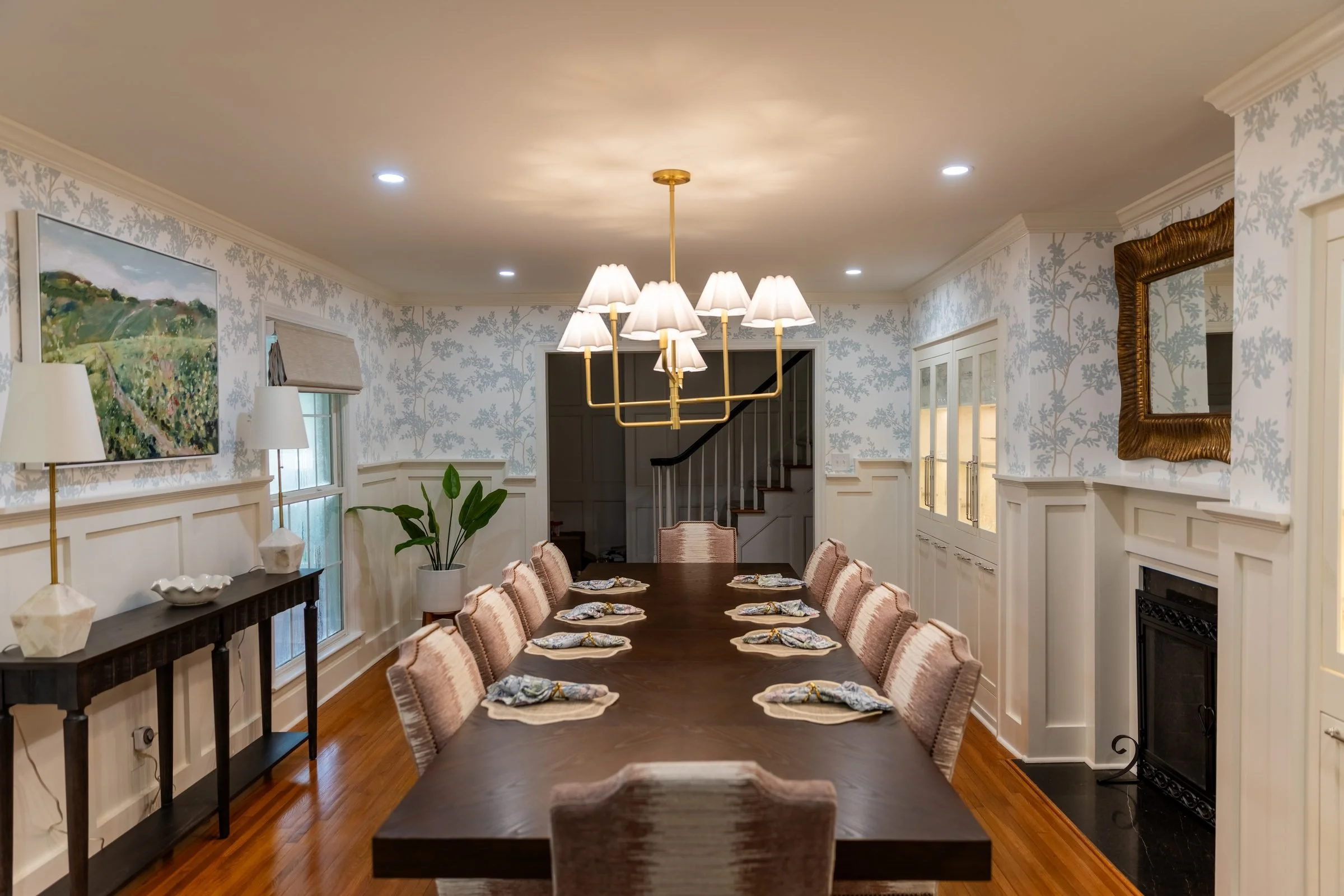 Formal dining room with blue toile wallpaper, white wainscoting, and brass chandeliers from a Charlotte, NC whole-home renovation
