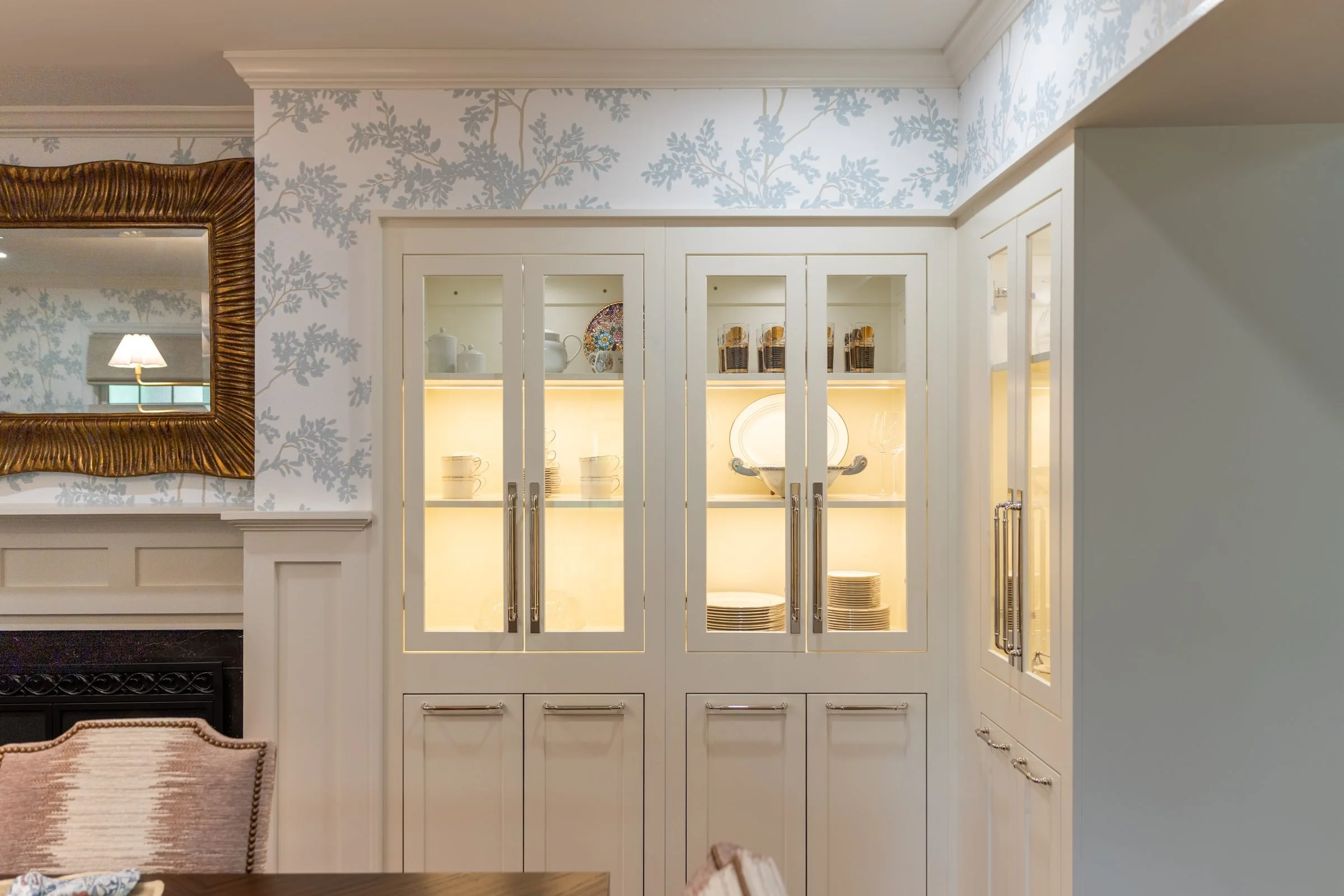 Lighted built-in china cabinets with glass doors set into blue toile walls in a renovated Charlotte, NC dining room