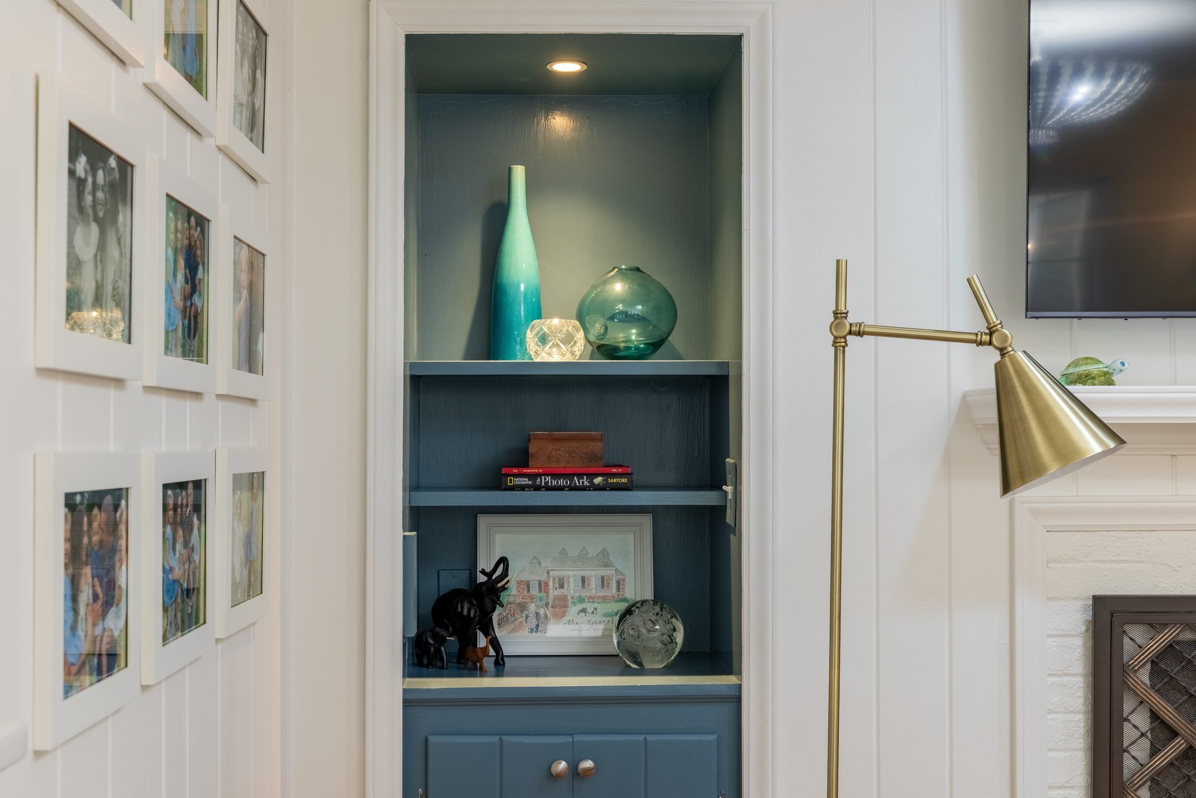 Built-in shelving niche with blue interior and brass reading lamp in a renovated Charlotte, NC living space