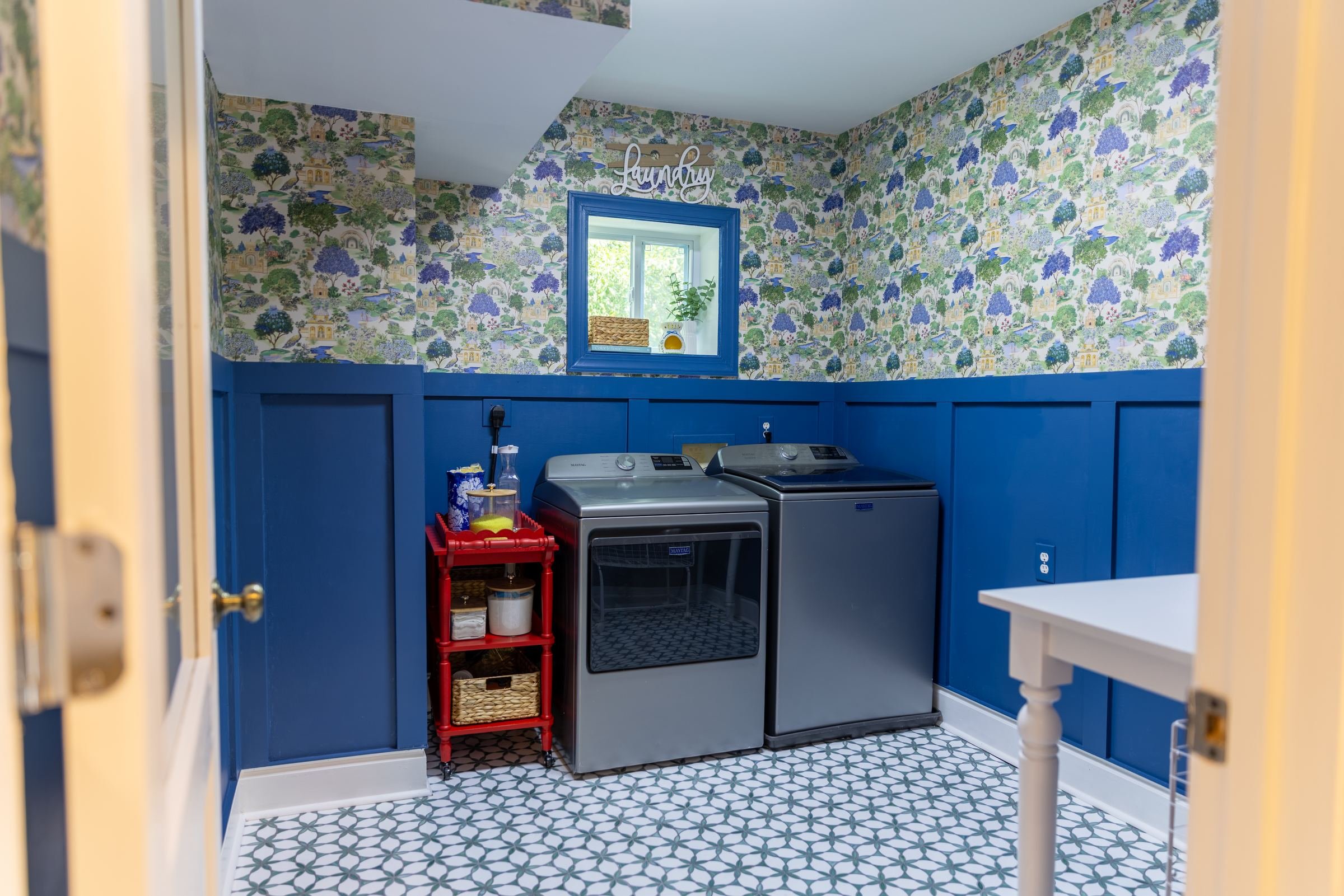 Laundry room with cobalt blue wainscoting, botanical wallpaper, and patterned floor tile in a Charlotte, NC home