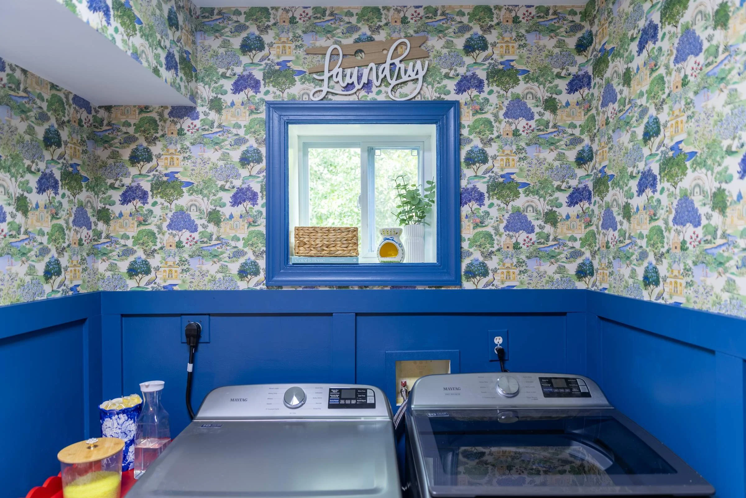 Laundry room with side-by-side washer and dryer under a blue-trimmed window and leafy wallpaper in Charlotte, NC