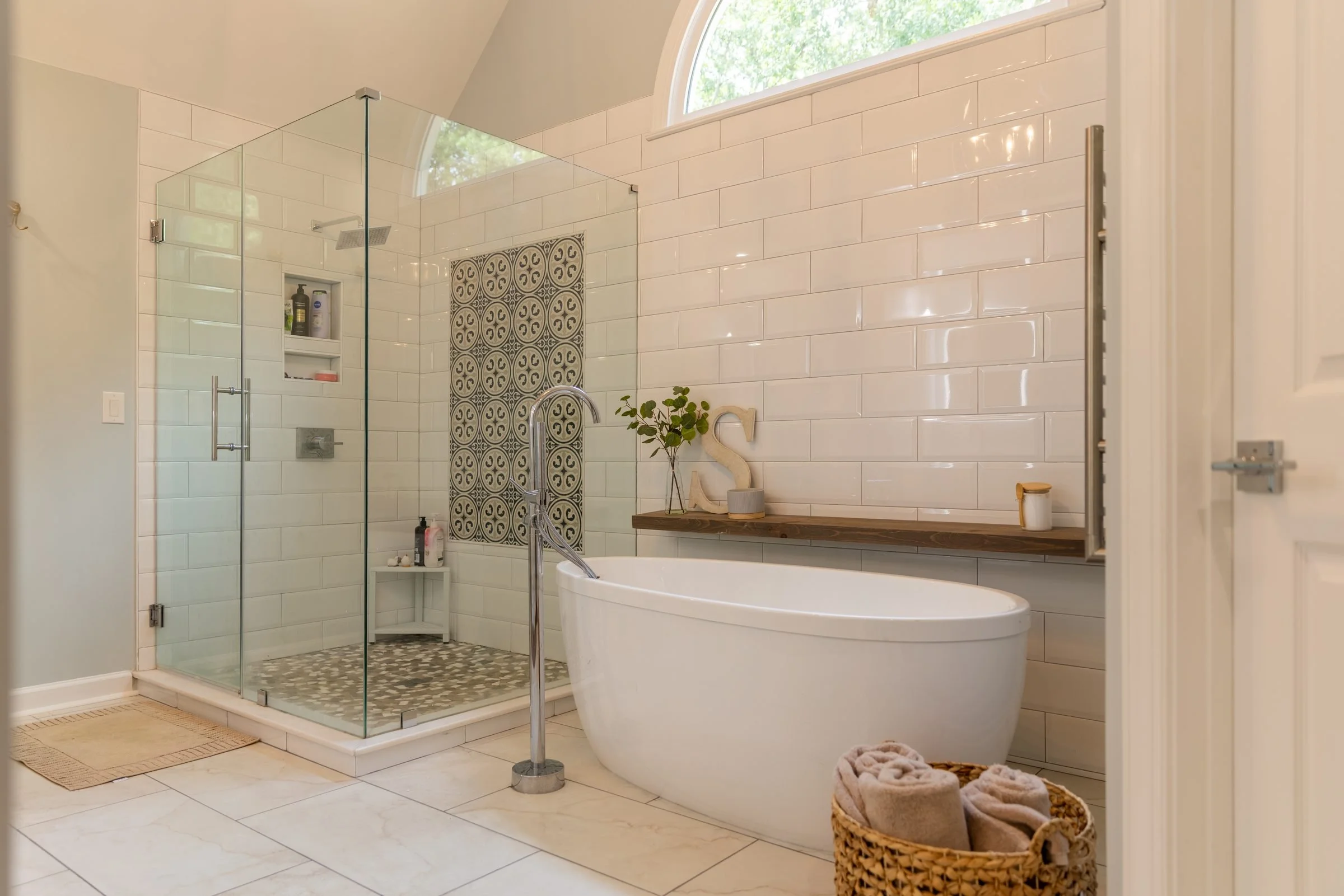 Primary bathroom with frameless glass shower, freestanding soaking tub, and subway tile from a Charlotte, NC renovation