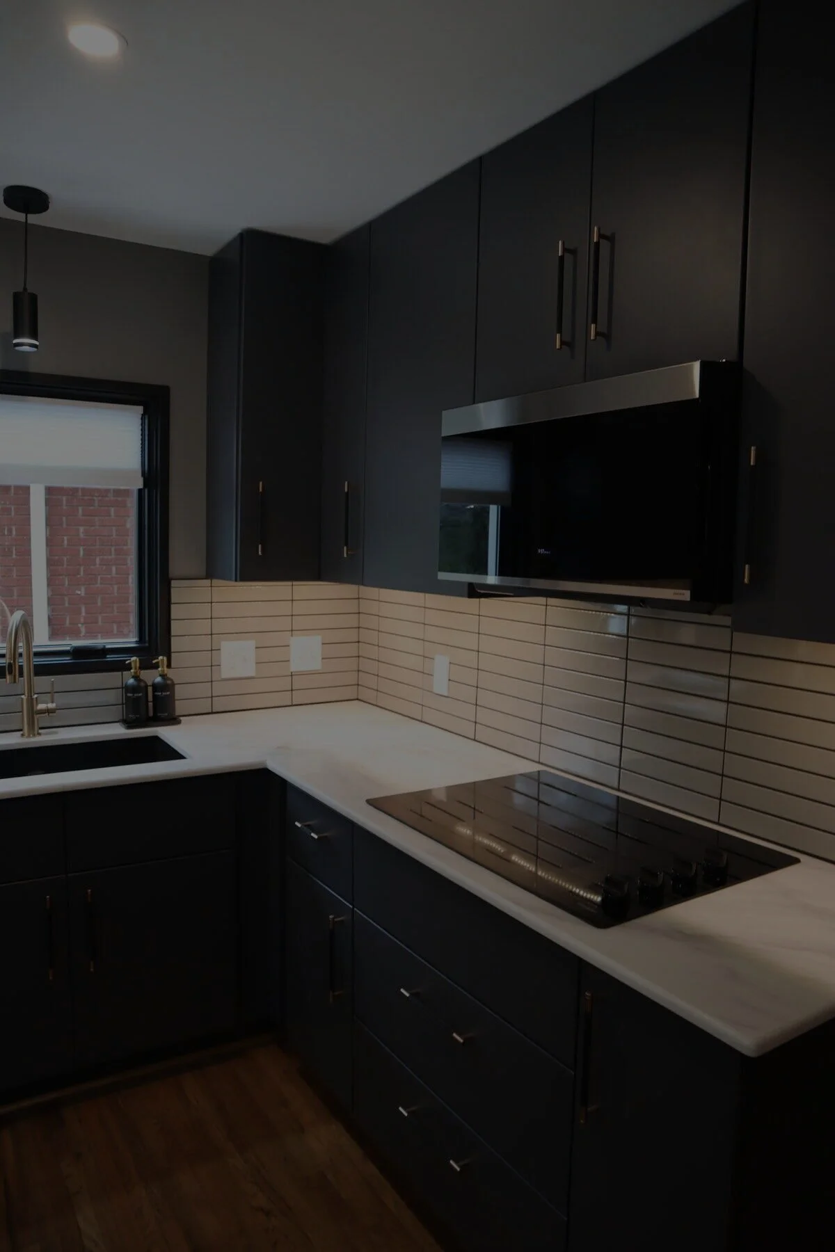 Close-up of custom black cabinetry, brass hardware, and tile backsplash from a Charlotte, NC kitchen remodel