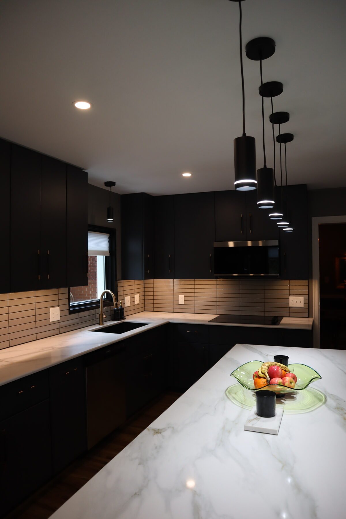 Modern kitchen remodel in Charlotte, NC with matte black cabinetry and waterfall-edge marble island