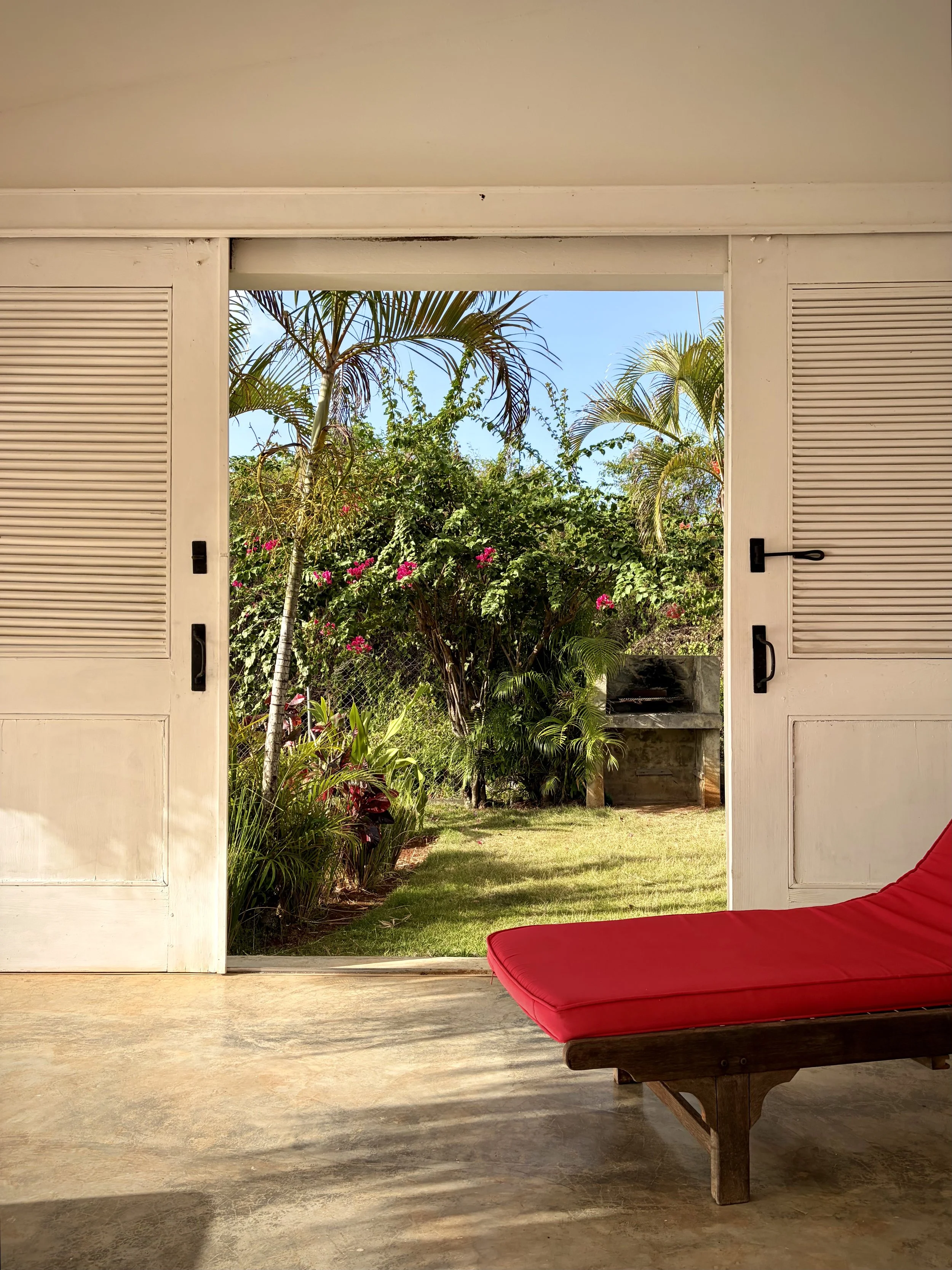 Two Caribbean-style doors open to the garden and the BBQ grill, located next to the terrace.