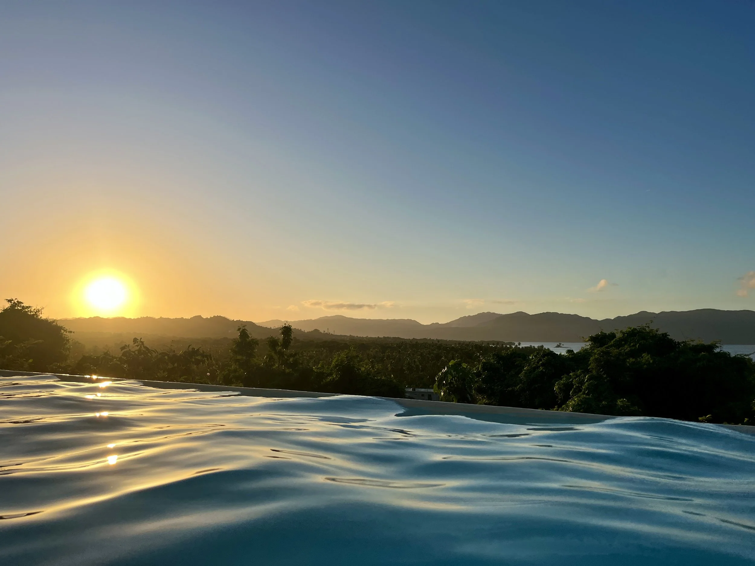 Sunset from the pool with views over the sea and the surrounding mountains.