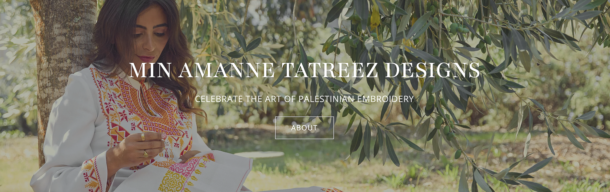 Woman sitting outdoors under an olive tree, engaging in Palestinian embroidery, wearing a white dress with colorful embroidery Tatreez Kit YA SOKO