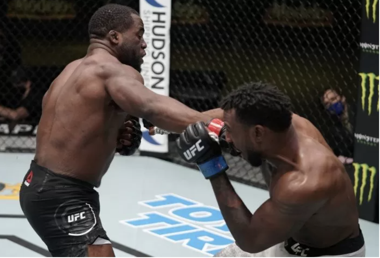 Tafon and other UFC fighter in a match, with one fighter delivering a punch to the other's face inside a cage.