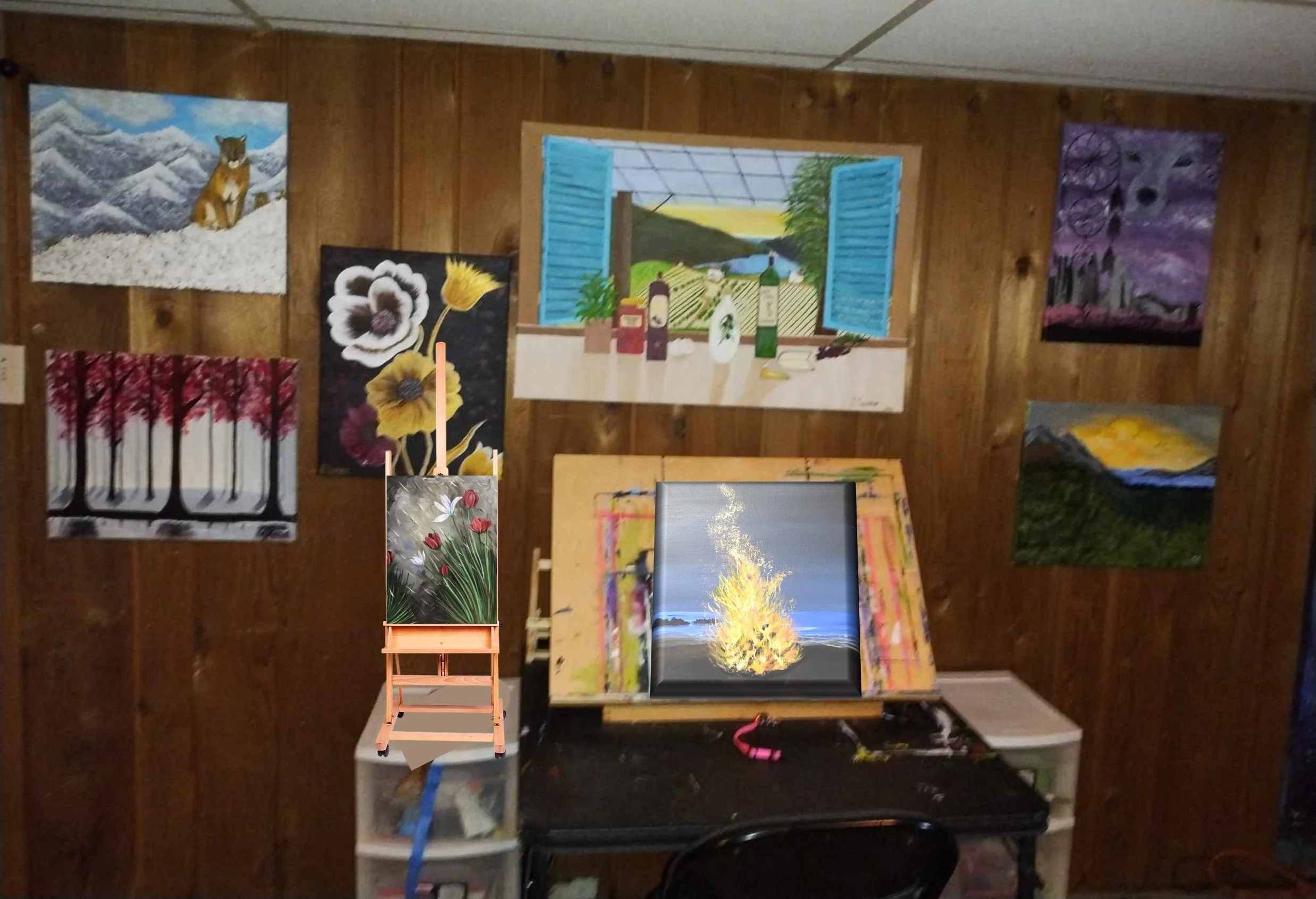The artist's art studio with wooden paneled walls displaying various colorful paintings, a small table with art supplies, and a partially completed artwork of a campfire or fire in a landscape.