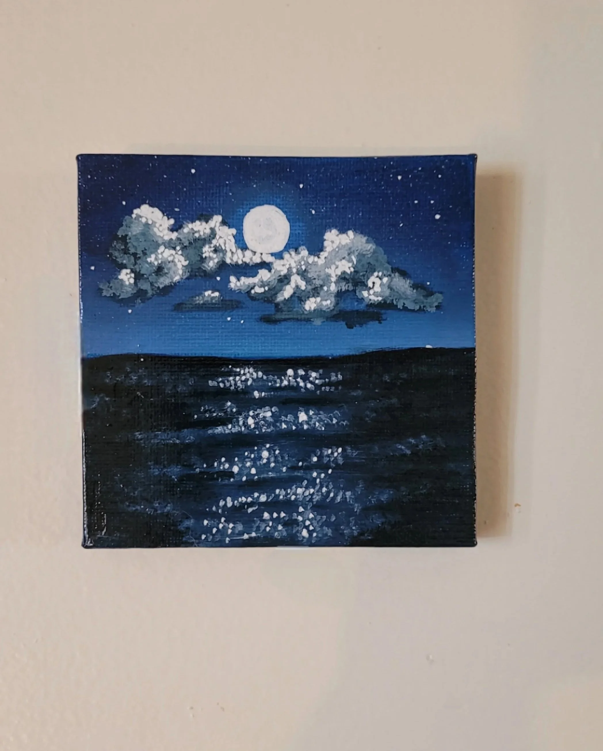 A painting of a moonlit night sky over a water body with clouds and the reflection of the moon on the water.