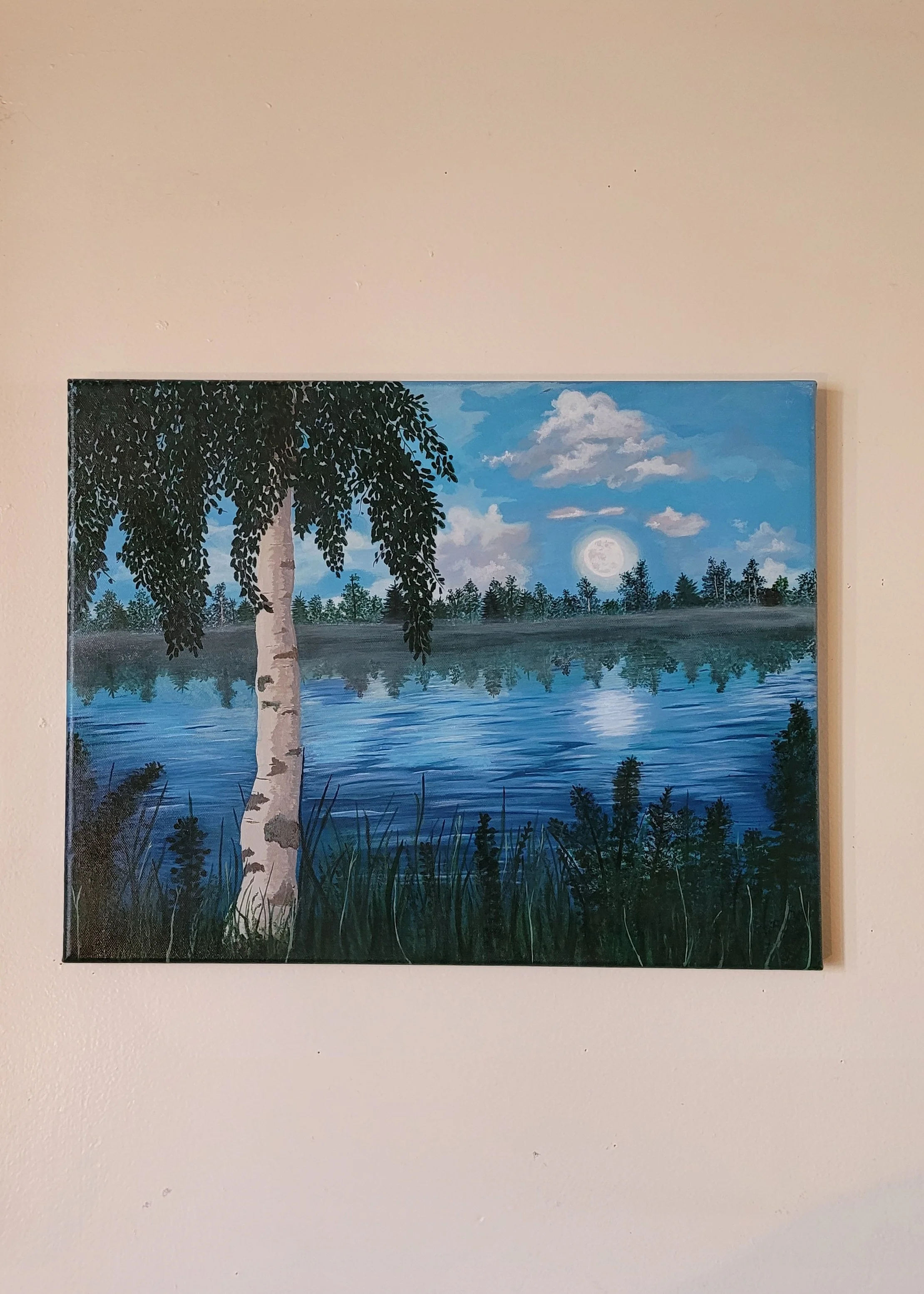 A painting of a lakeside scene at night featuring a birch tree in the foreground, calm water reflecting the moon and clouds, with a forest in the background and a clear blue sky. Hidden Bigfoot.