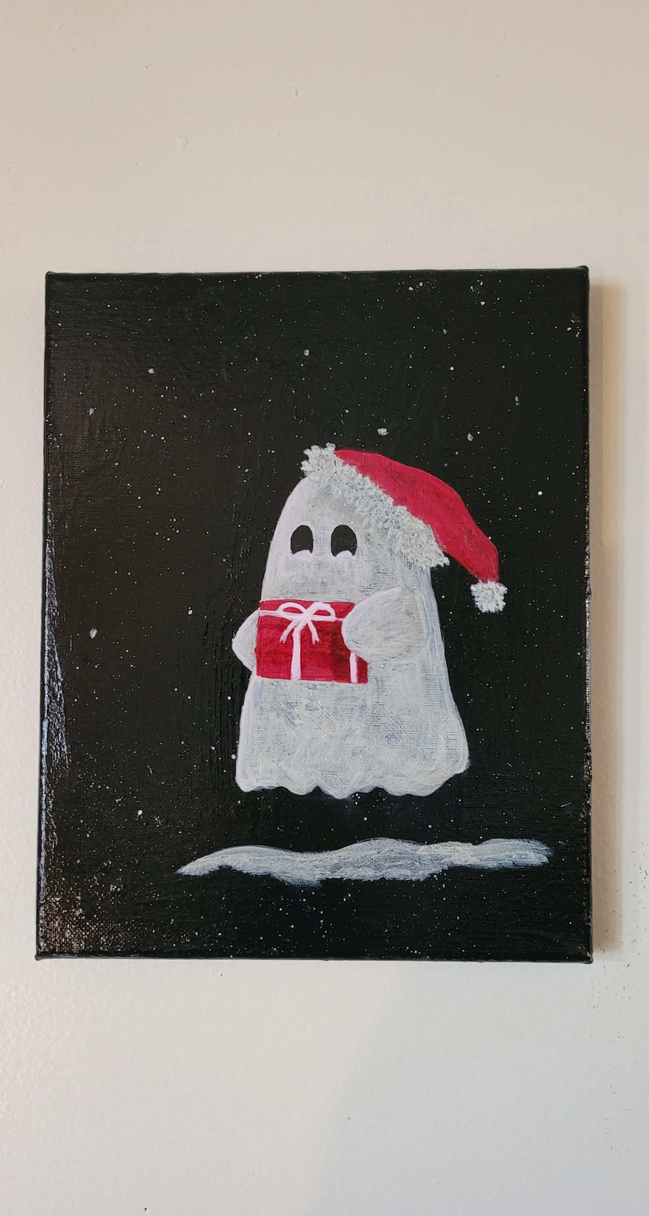 A painting of a cute ghost wearing a red Santa hat, holding a red gift box with a white bow, on a black background with snow falling.