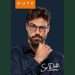 A man with glasses and a beard in dark clothing, resting his chin on his hand, against a dark background, with the text 'So Dutz.' and a logo reading 'DUTZ' in the top left corner.