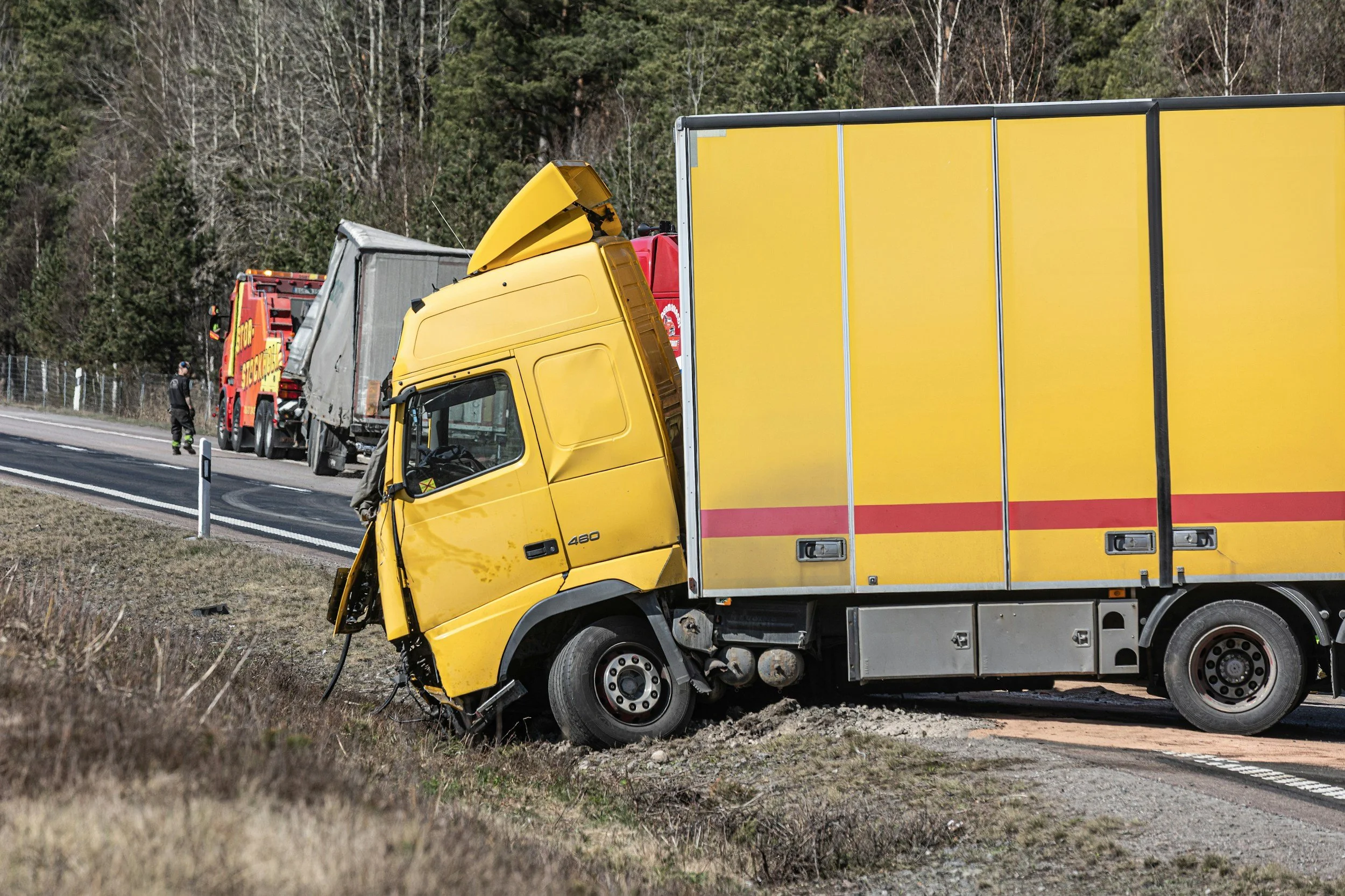 A yellow truck parked on the roadside, surrounded by greenery and a clear blue sky.