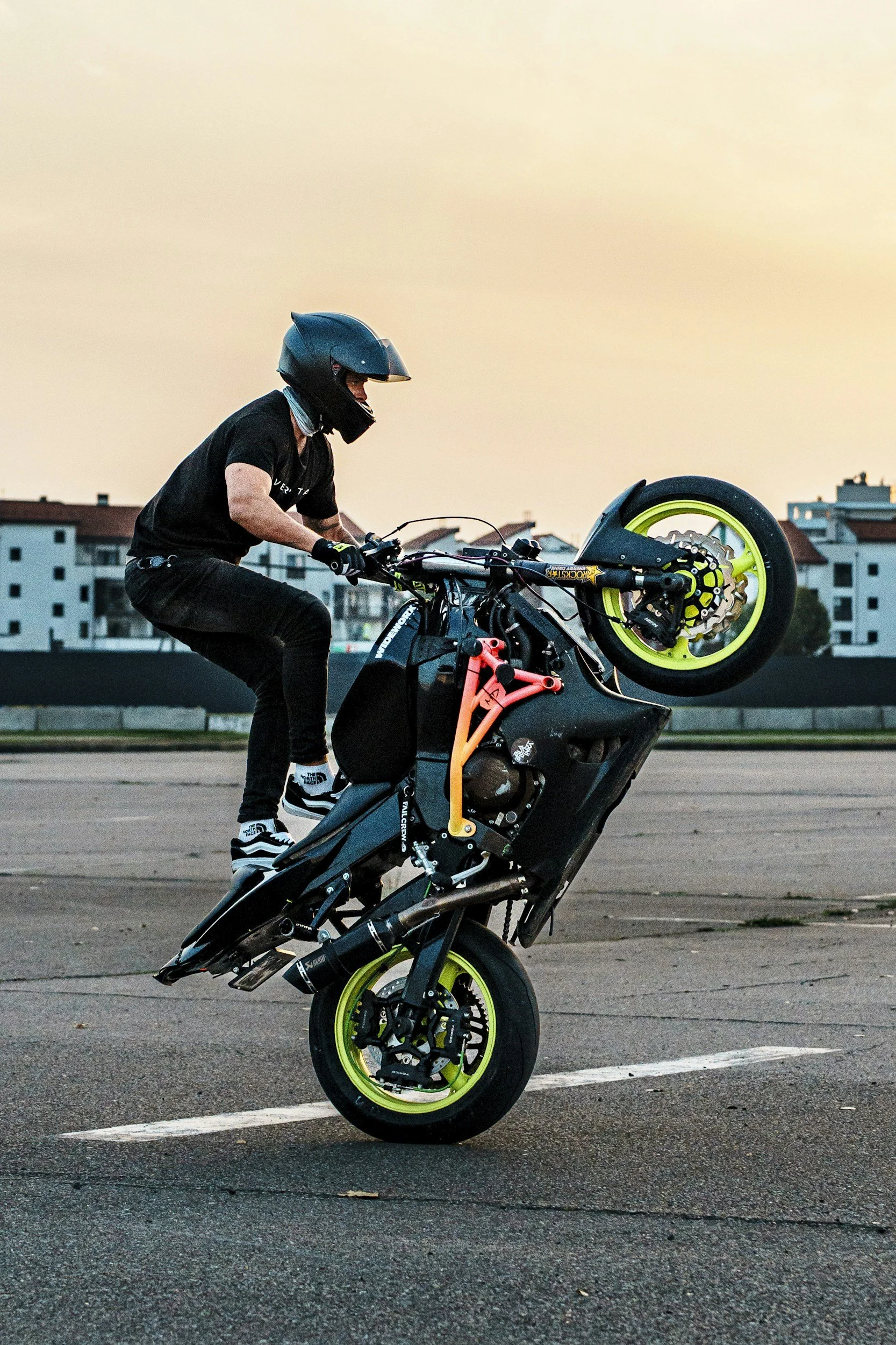 Person performing a stunt on a motorcycle in a parking lot during sunset.