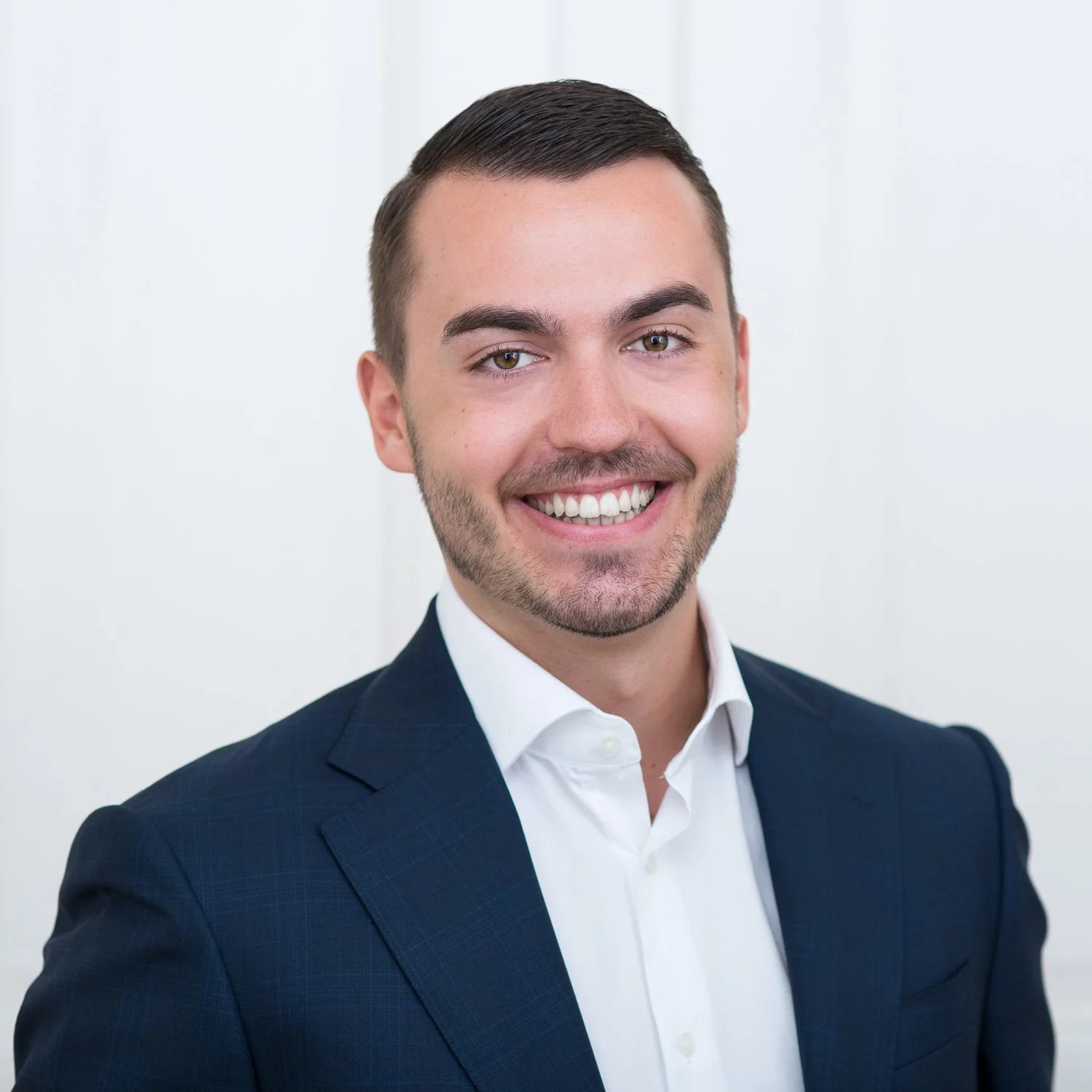 Mann und Anzug lächelt in die Kamera.