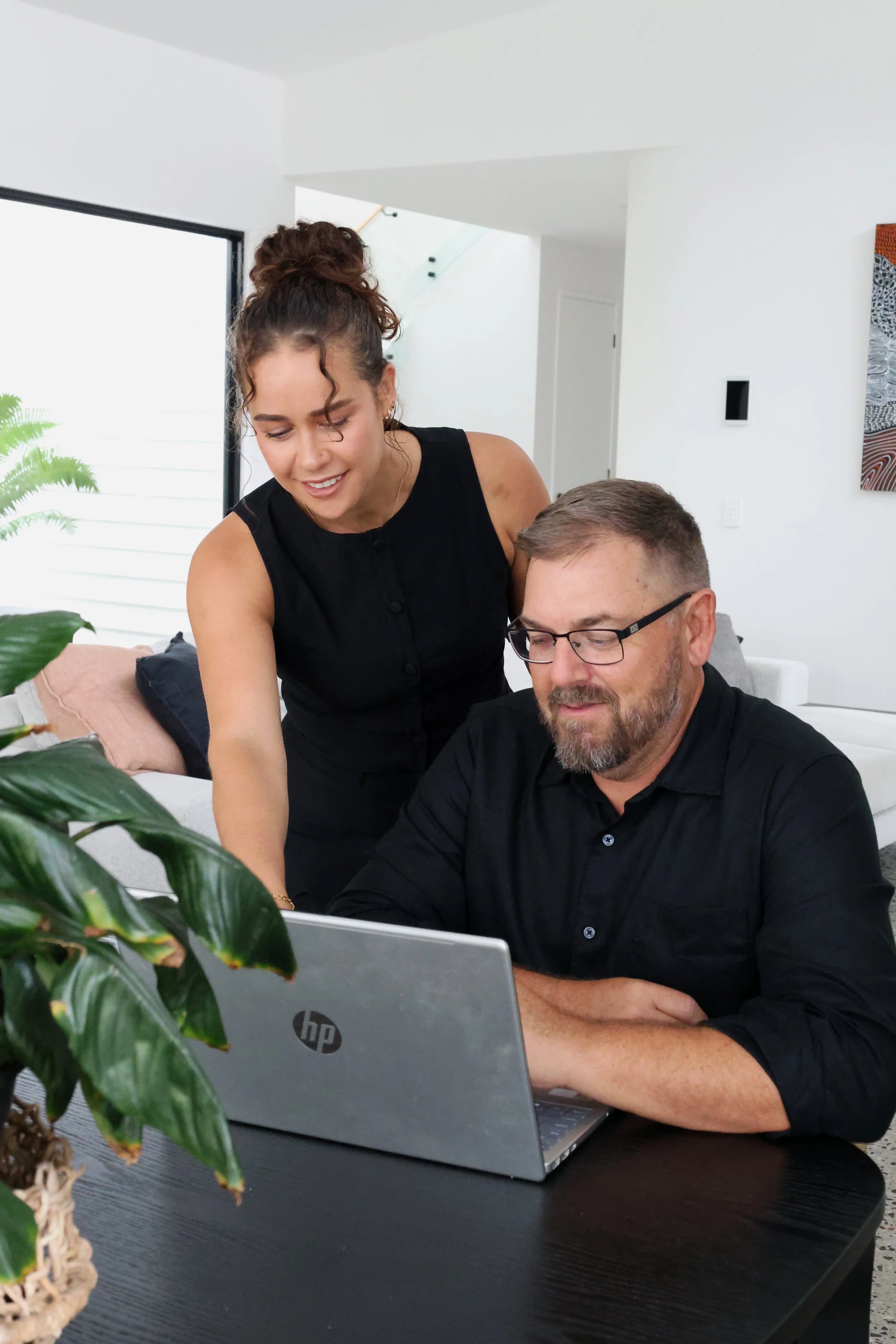 Tara Rockett, Senior Finance Broker & Scott are working in the office on a laptop, undertaking a mortgage review.