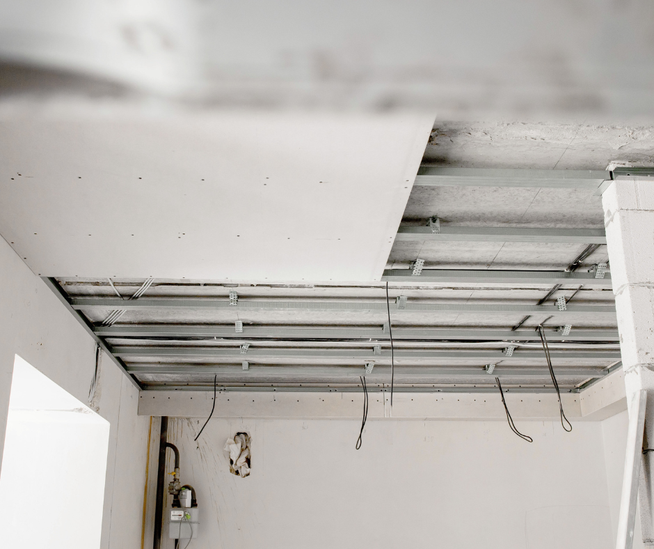 Interior ceiling under construction with exposed metal framing and electrical wiring, drywall partially installed.