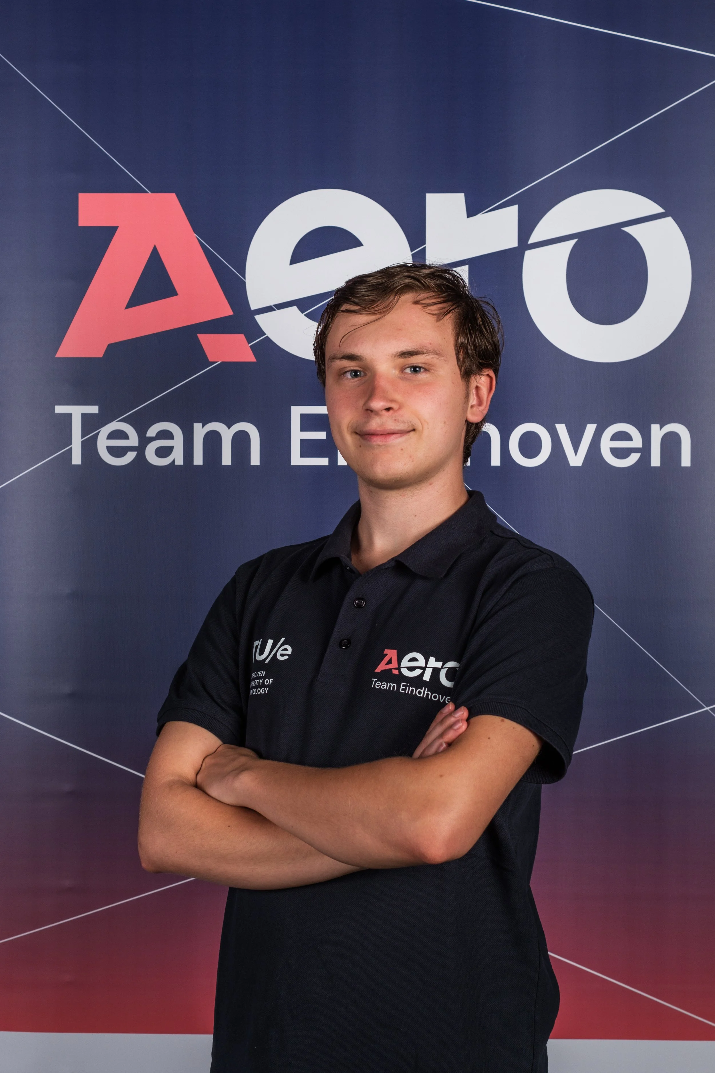 Young man with crossed arms standing in front of a backdrop with the text "Aero" and "Team Eindhoven."