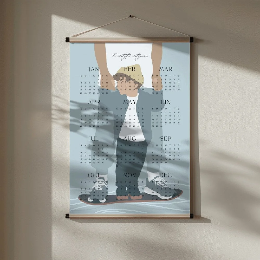 Minimalistischer Wandkalender 2026 von Tine Taler – das ganze Jahr auf einen Blick, mit Papa-Sohn-Motiv auf Skateboard in pastelligen Blautönen.