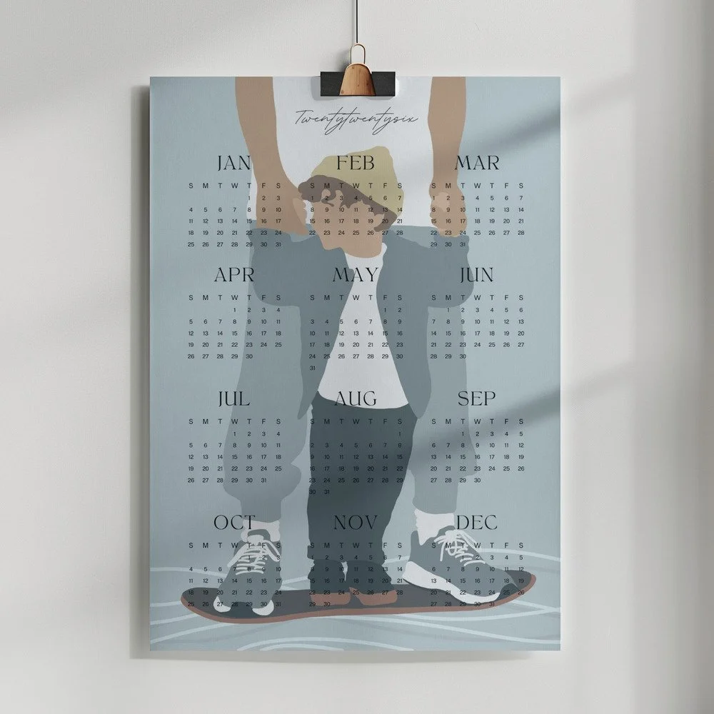 Minimalistischer Wandkalender 2026 von Tine Taler – das ganze Jahr auf einen Blick, mit Papa-Sohn-Motiv auf Skateboard in pastelligen Blautönen.