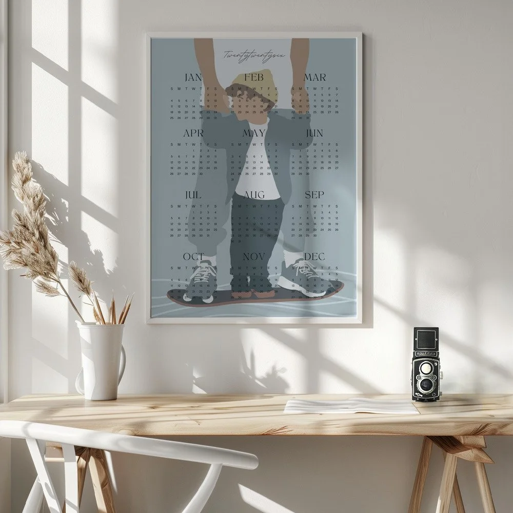 Minimalistischer Wandkalender 2026 von Tine Taler – das ganze Jahr auf einen Blick, mit Papa-Sohn-Motiv auf Skateboard in pastelligen Blautönen.