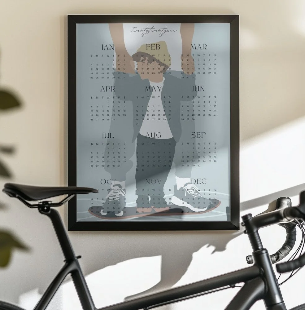 Minimalistischer Wandkalender 2026 von Tine Taler – das ganze Jahr auf einen Blick, mit Papa-Sohn-Motiv auf Skateboard in pastelligen Blautönen.