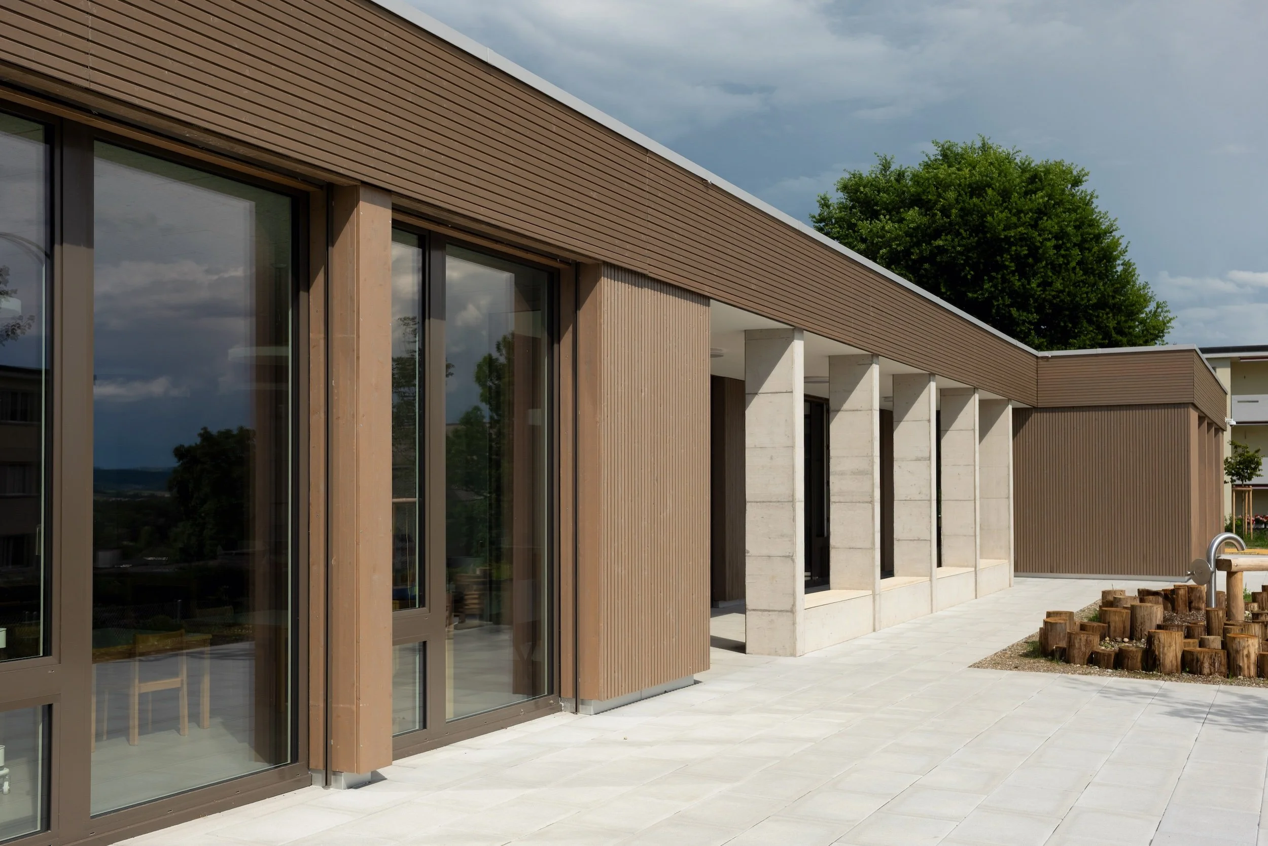 Modern architecture photography by Dario Caduff featuring the wooden facade and concrete pillars of the Schulhaus Letten school building in Switzerland.