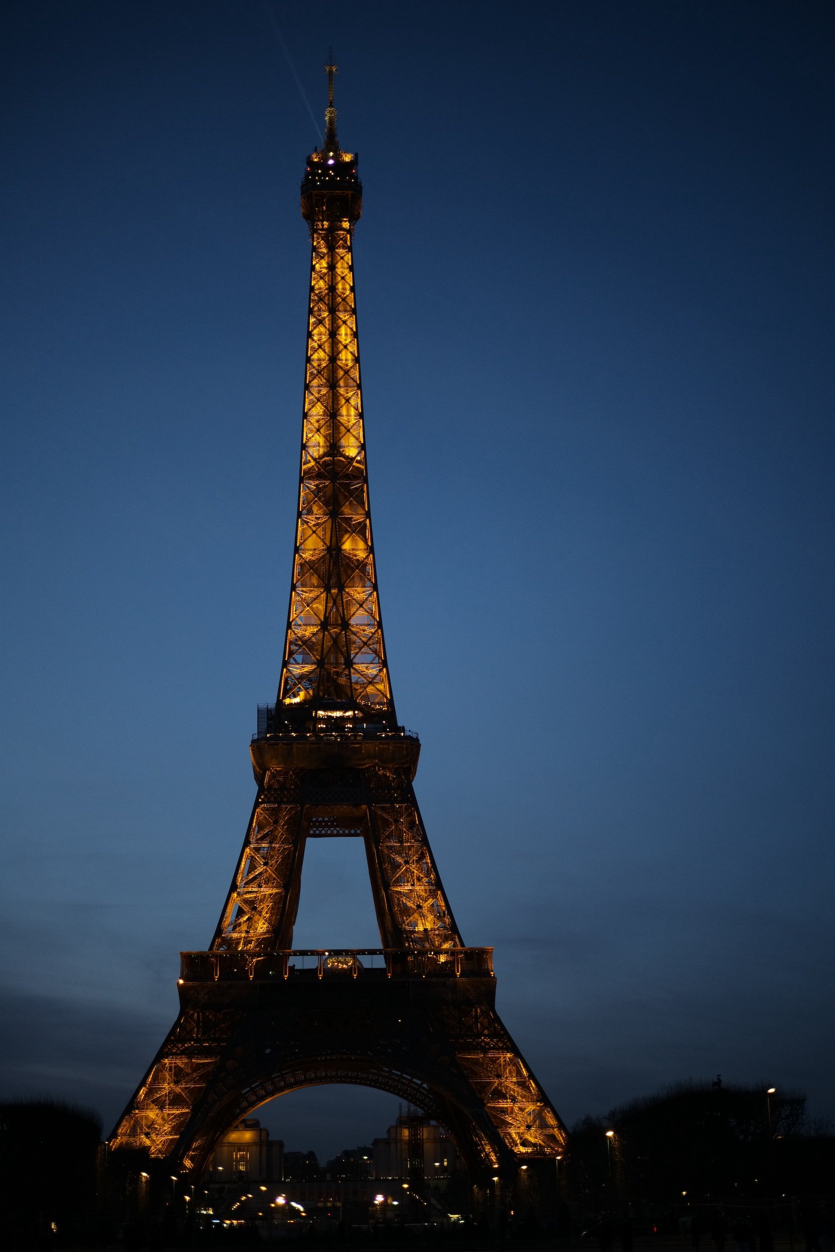 Der Eiffelturm bei Nacht, hell beleuchtet, gegen einen dunklen blauen Himmel.