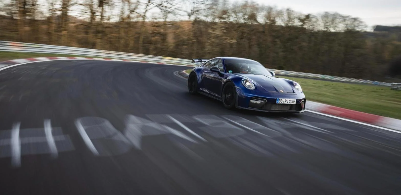 Blue Porsche 911 GT3 cornering at speed on the Nürburgring Nordschleife