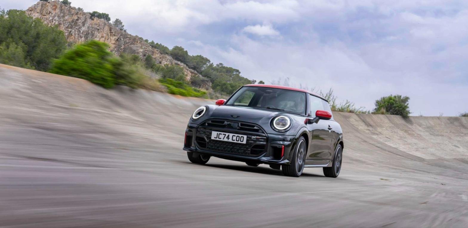 Dark grey Mini John Cooper Works hatch with red roof cornering on a banked track
