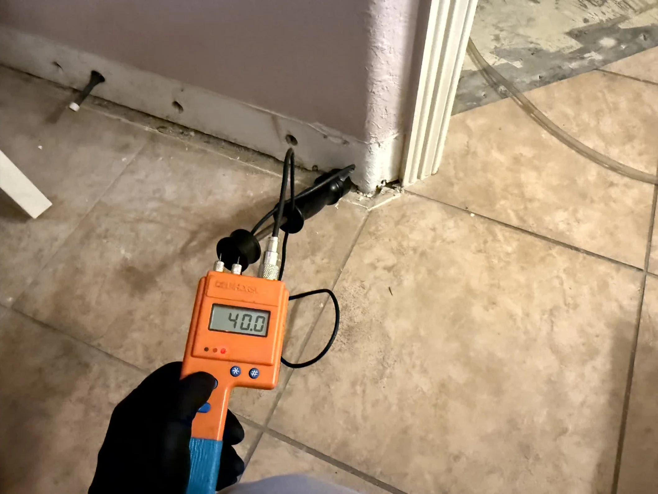 Checking moisture levels with hammer probe meter in Central Texas home.