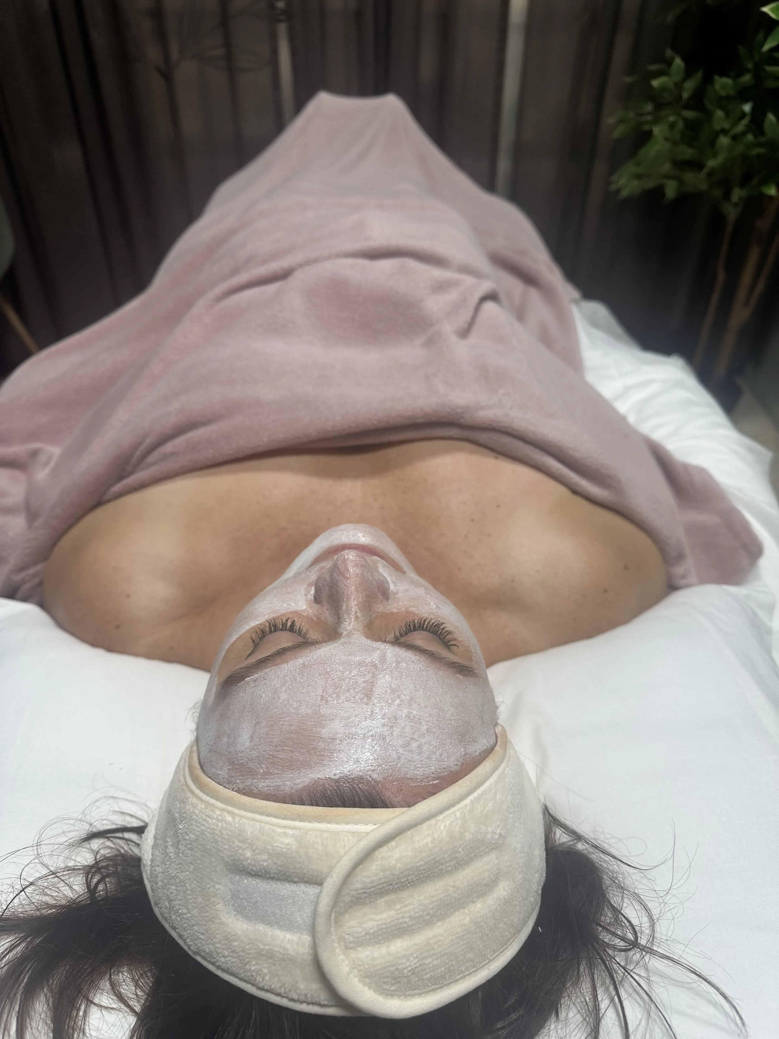 A woman is lying on a table receiving a facial