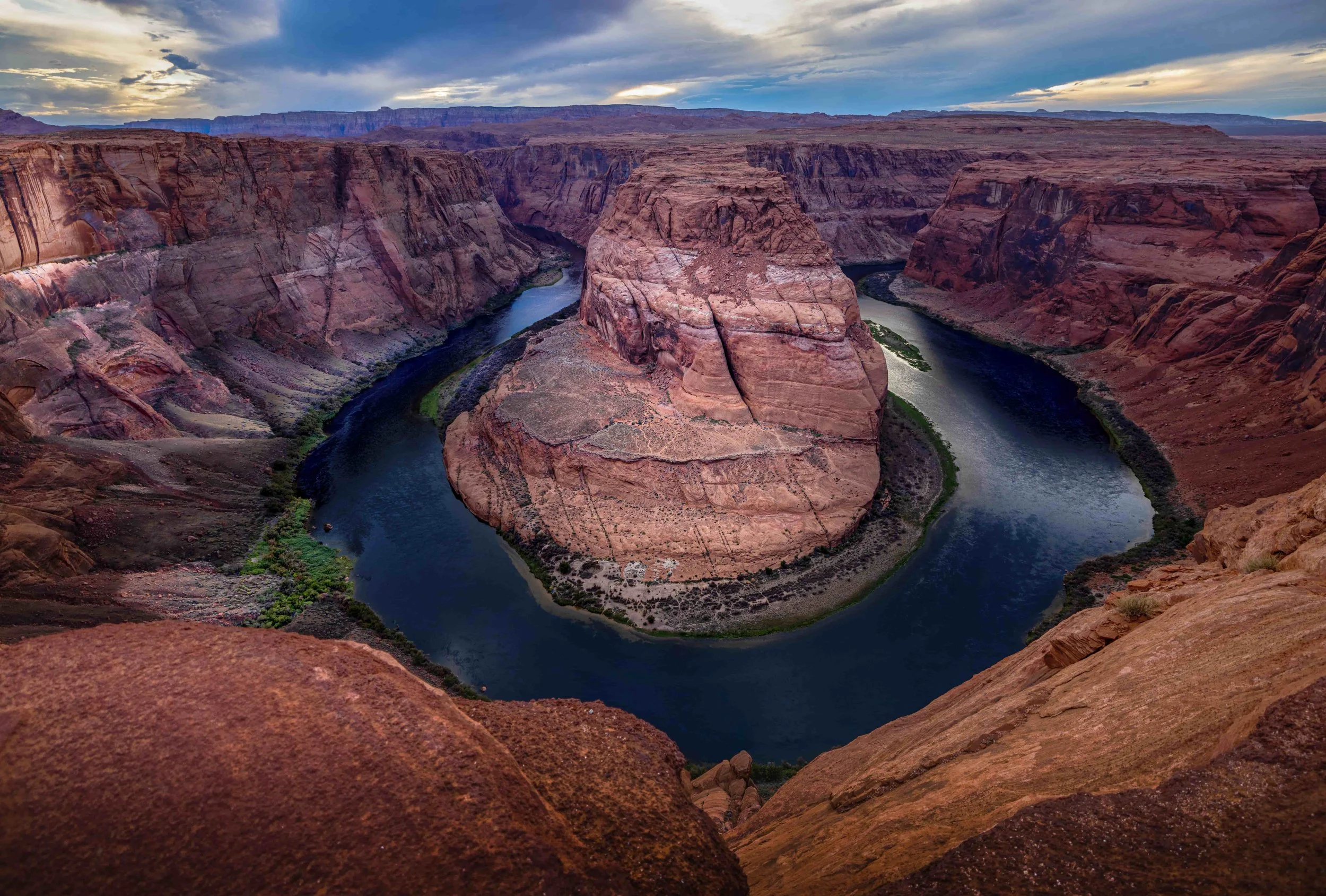 Der Colorado River schlingert um einen großen, runden Felsen in der Mitte des Grand Canyon bei Sonnenuntergang.
