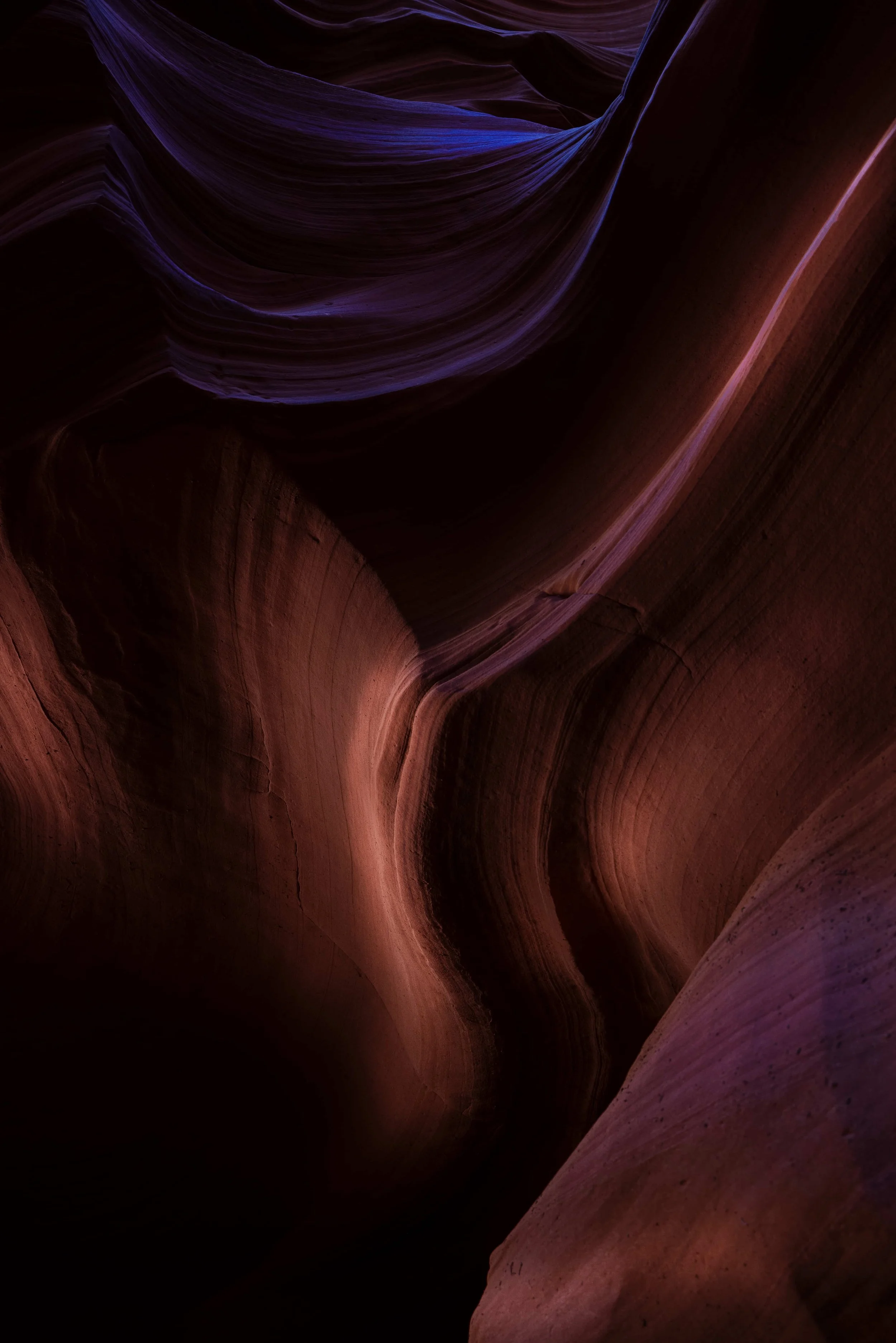 Farbige Felsenschlucht mit geschwungenen Wänden in Rot-, Braun- und Violetttönen.