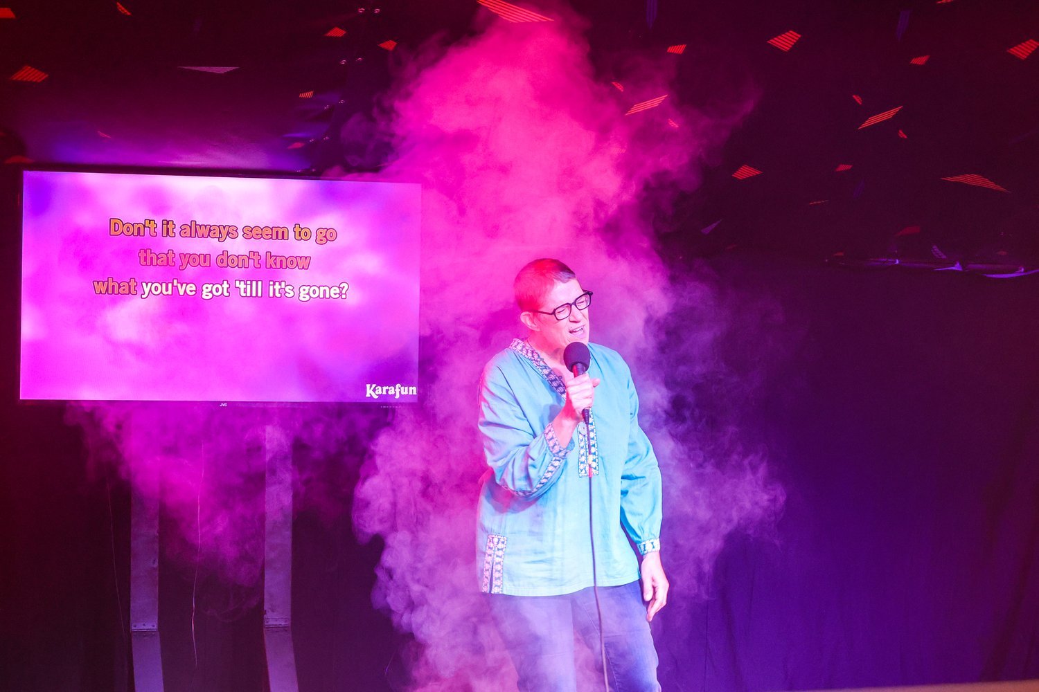 A person signing into a mic with a screen showing the lyrics behind them.