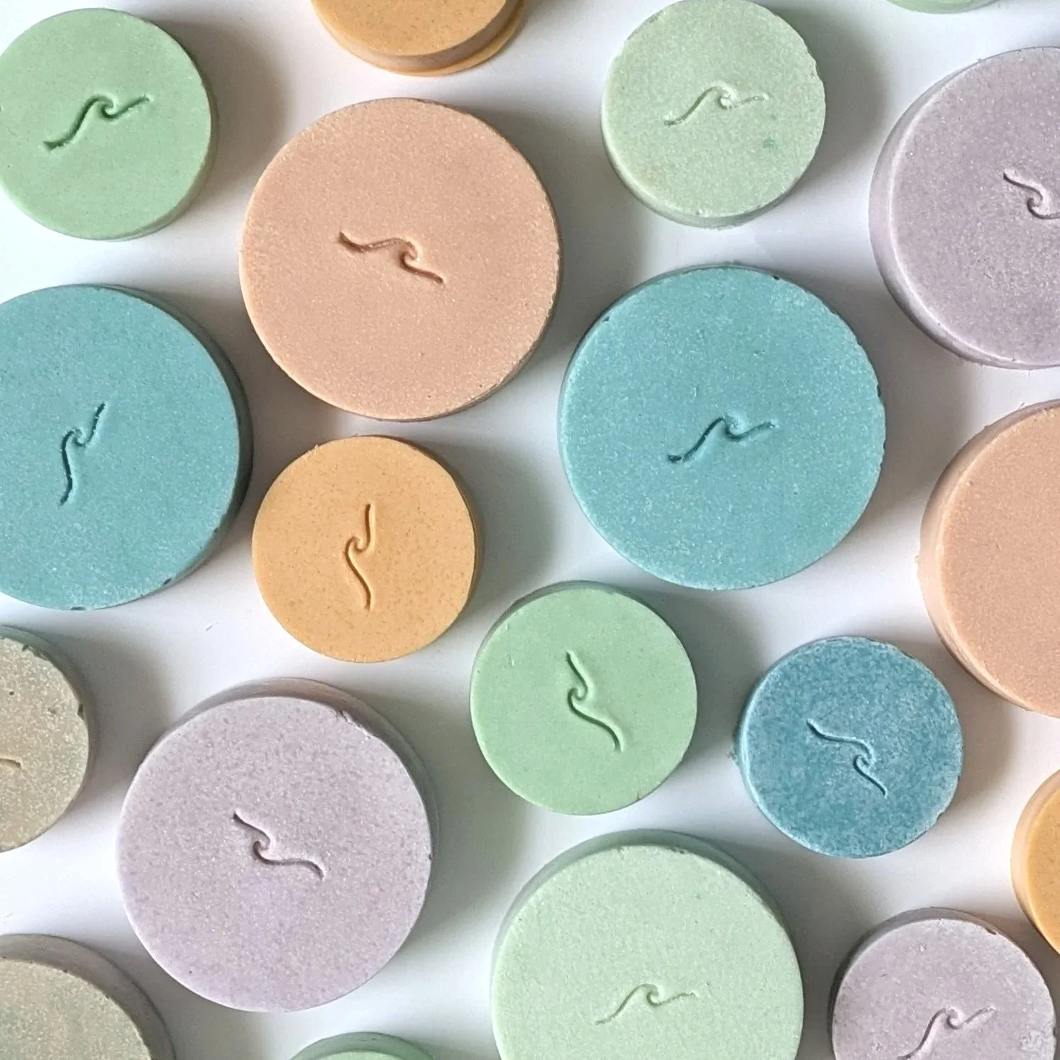 Colorful array of round sea salt soap bars with wave stamp.