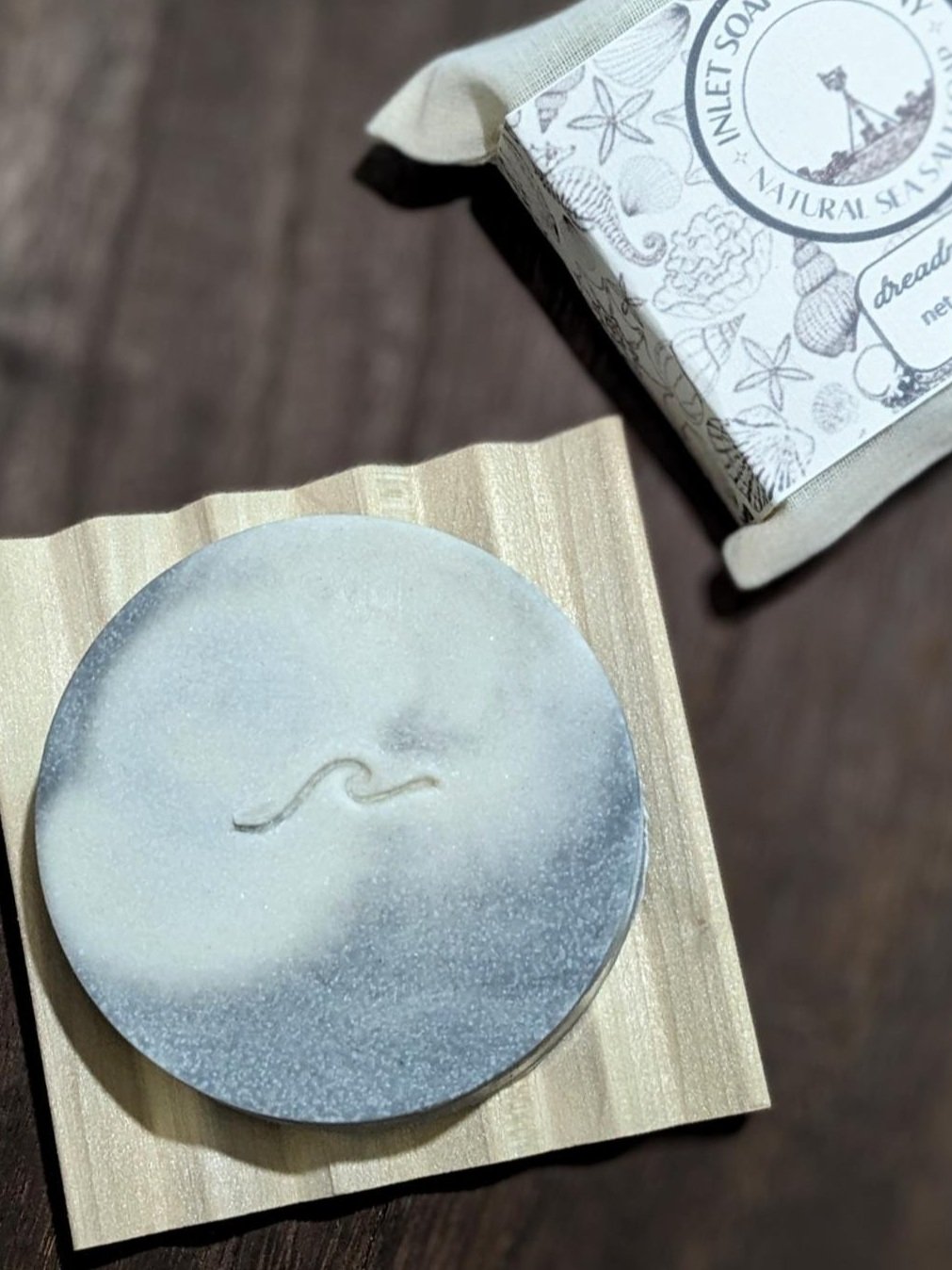 Dreadnaught soap bar resting on wooden soap dish – handmade ocean-inspired soap with dark swirl design